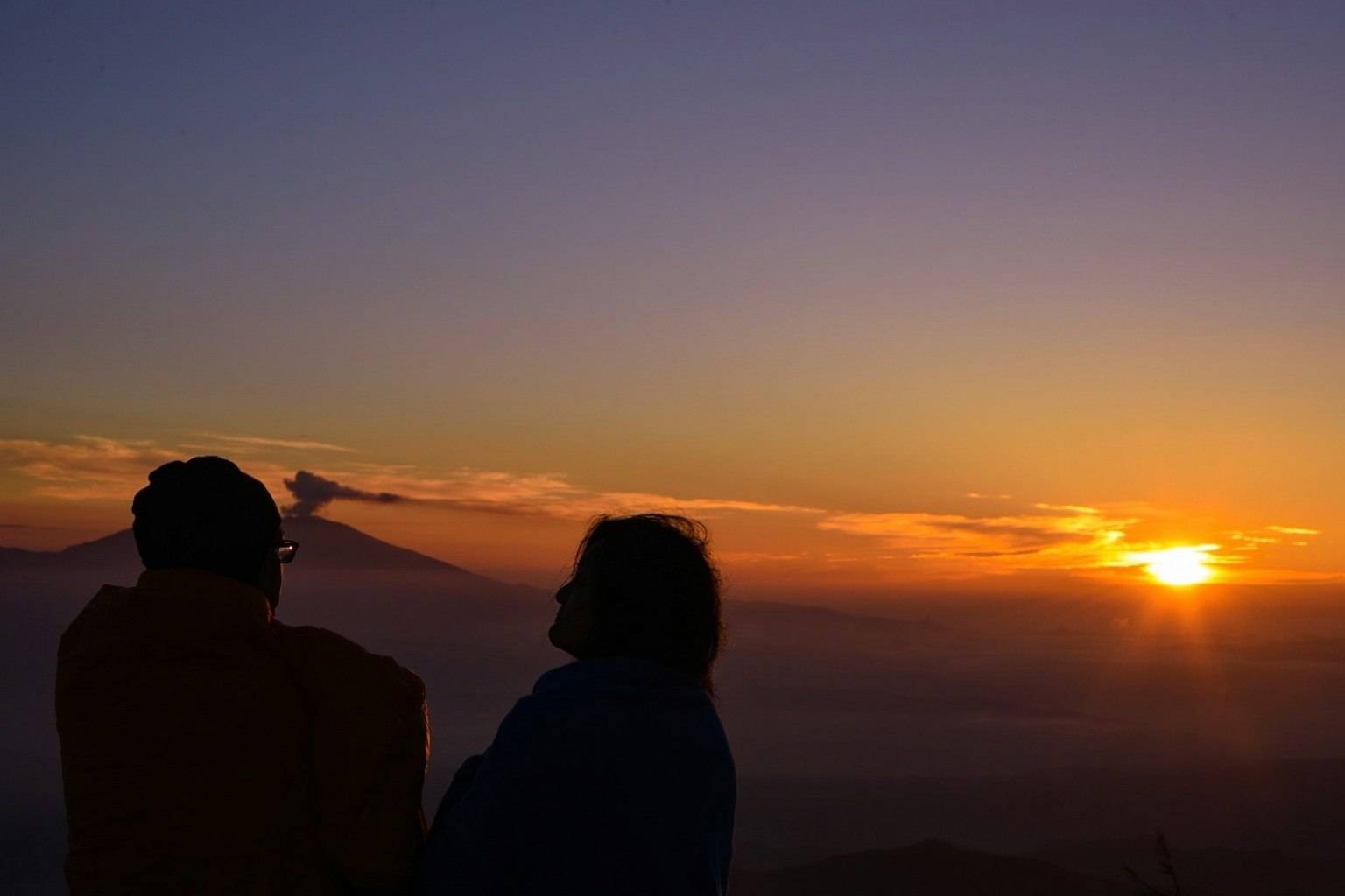 夕陽下兩個人的輪廓與山景