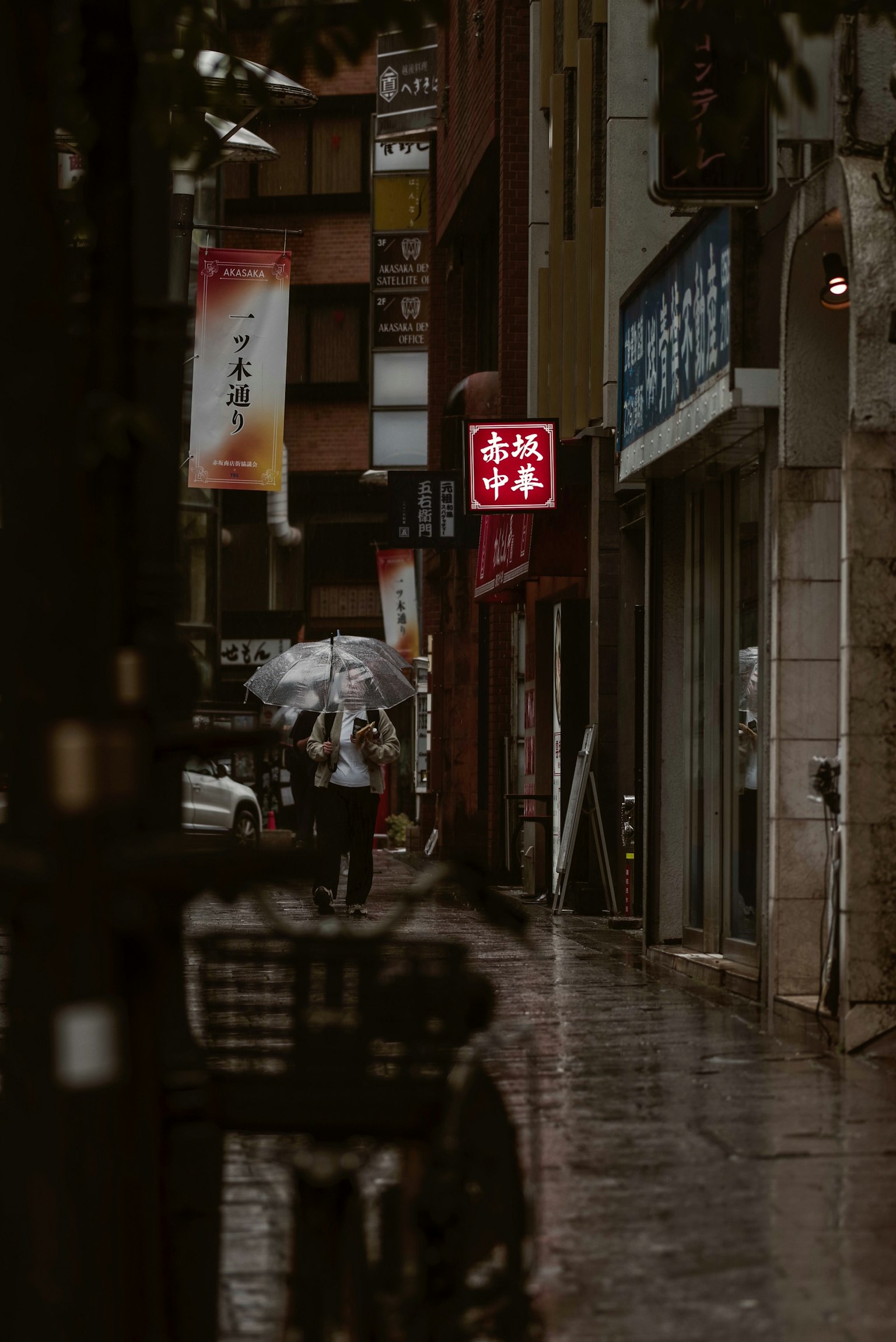 비 오는 날 거리를 걷는 사람들과 상점 간판이 있는 거리 풍경