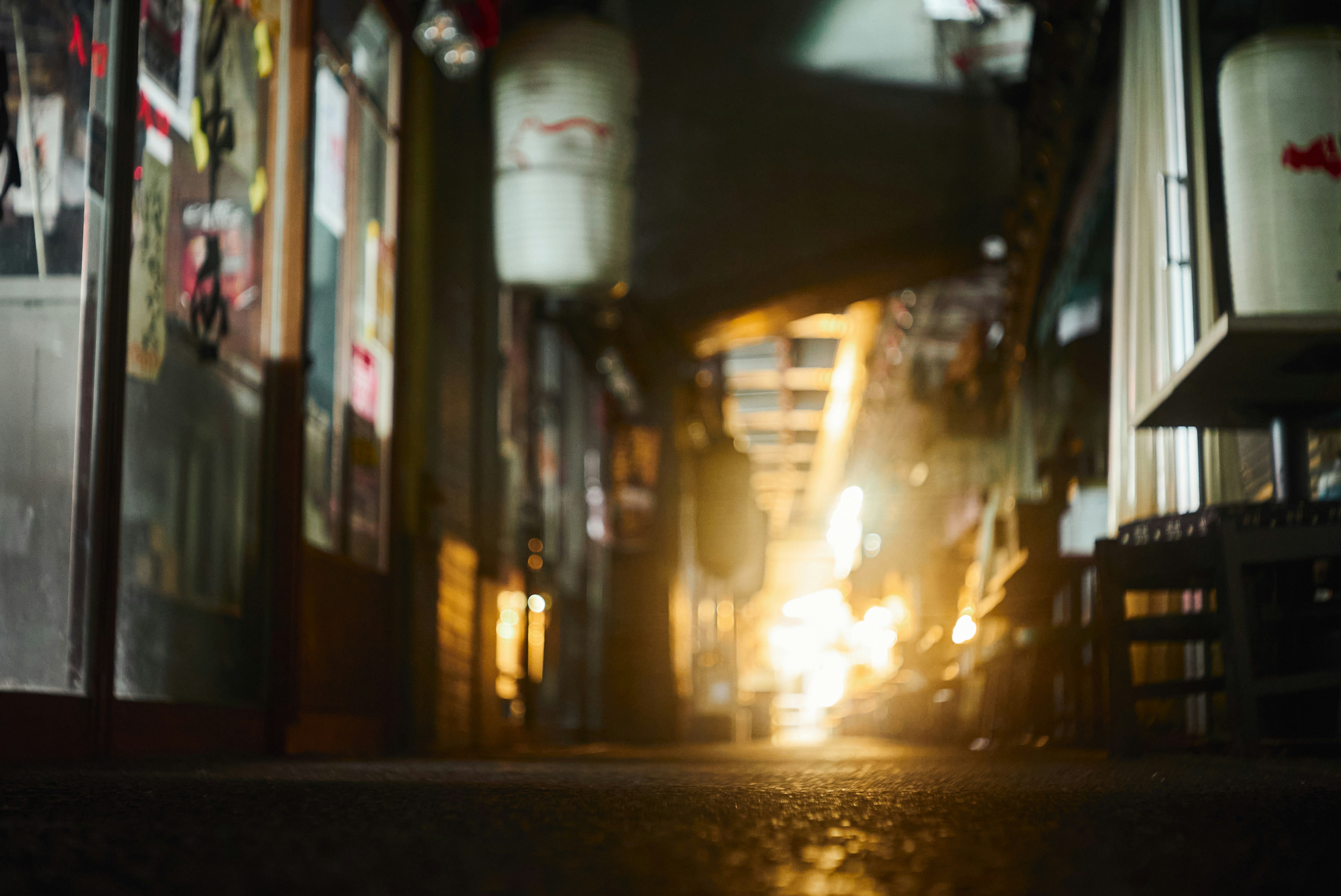 夕暮れの路地に並ぶ店先と看板のある抜け道