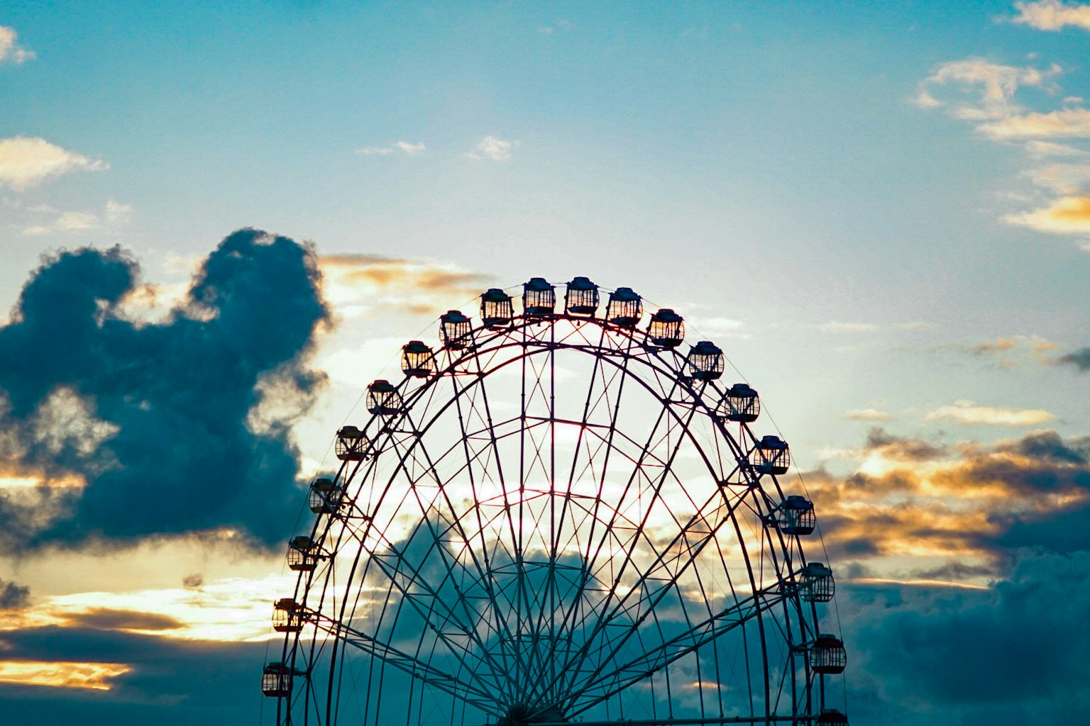 Silhouette of a Ferris wheel against a sunset sky