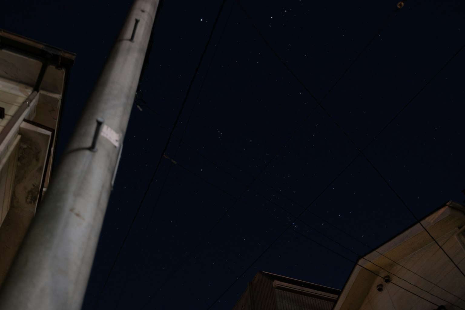 夜空に星が輝く中、電柱と住宅が見える風景
