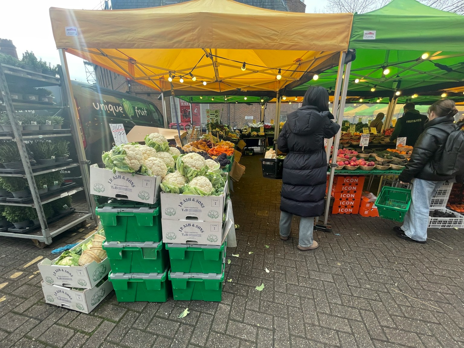 Puesto de verduras en un mercado con carpas coloridas y clientes