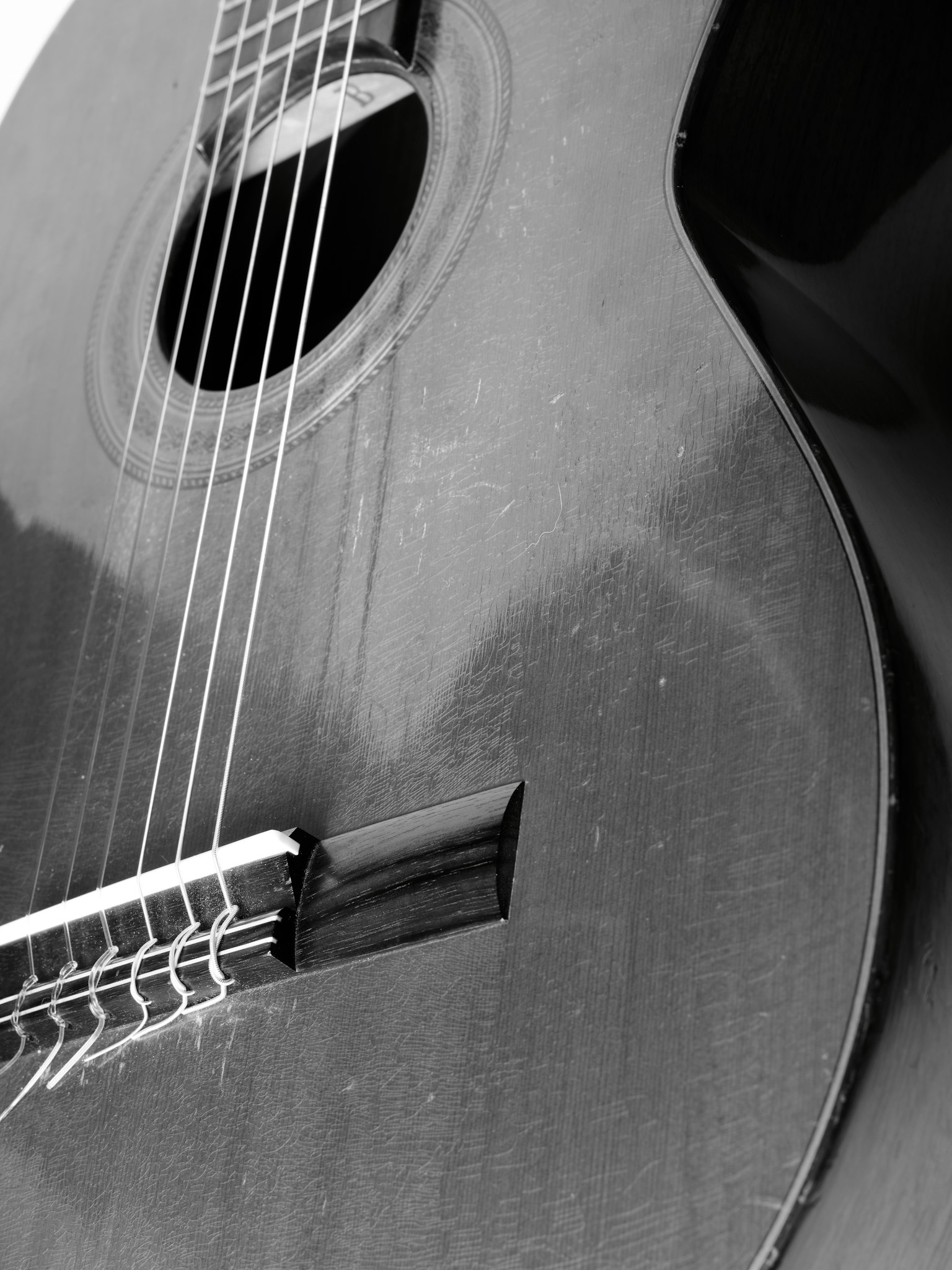 Close-up image of a black guitar showing strings and sound hole