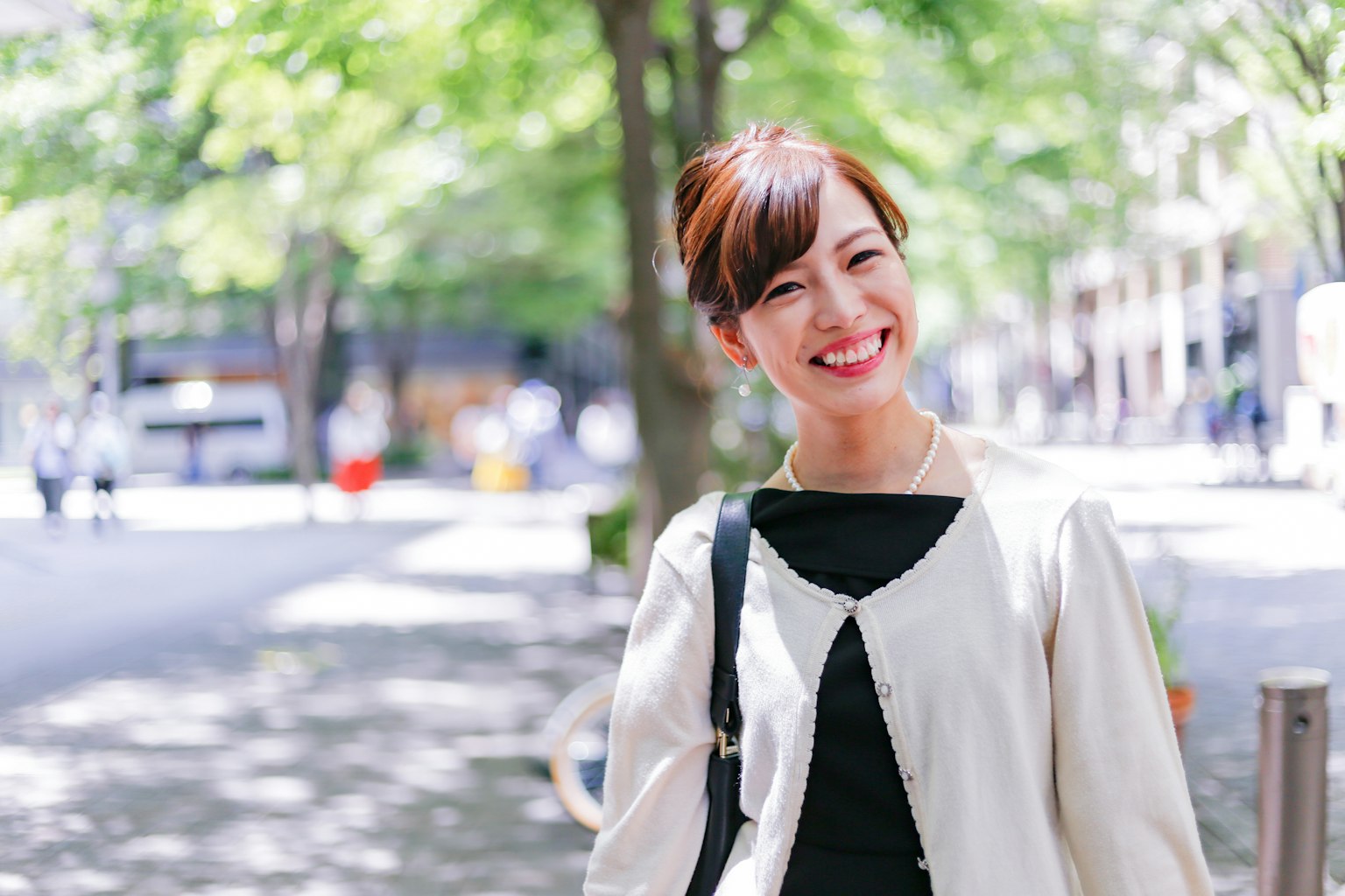 Mujer sonriente en un parque con árboles verdes de fondo