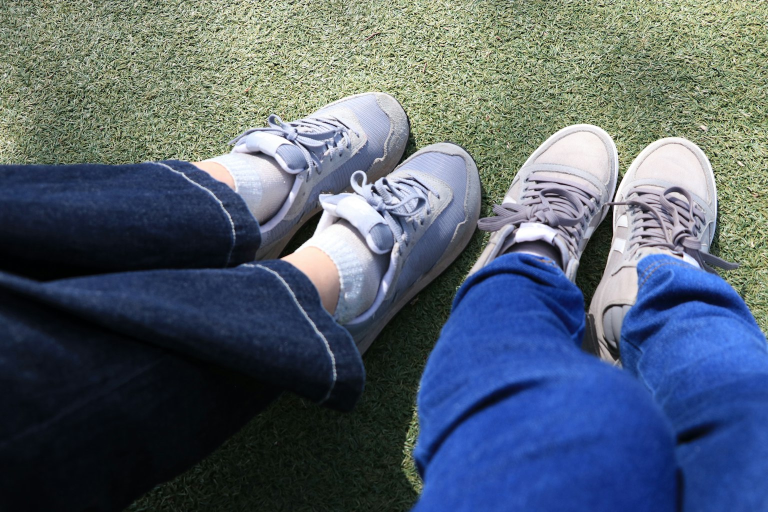 Foto, die zwei Paar Füße mit grauen Sneakers und blauen Jeans zeigt