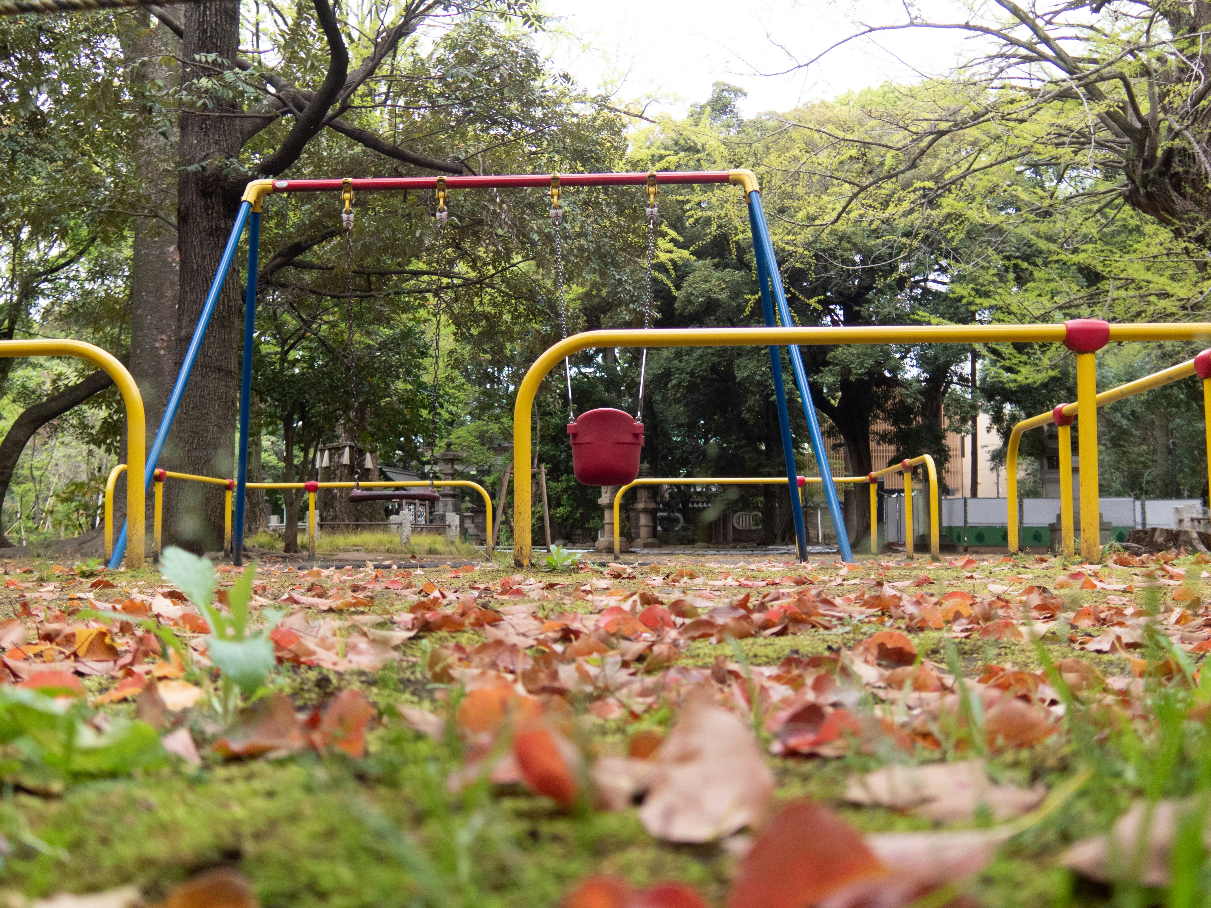 落ち葉の敷かれた秋の遊び場のブランコ周辺