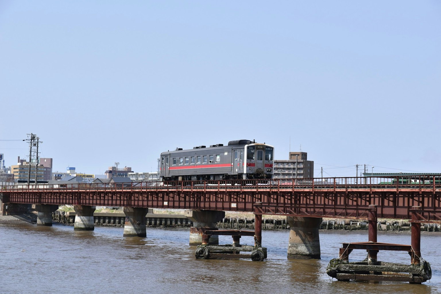 Tren cruzando un puente sobre un río con horizonte urbano