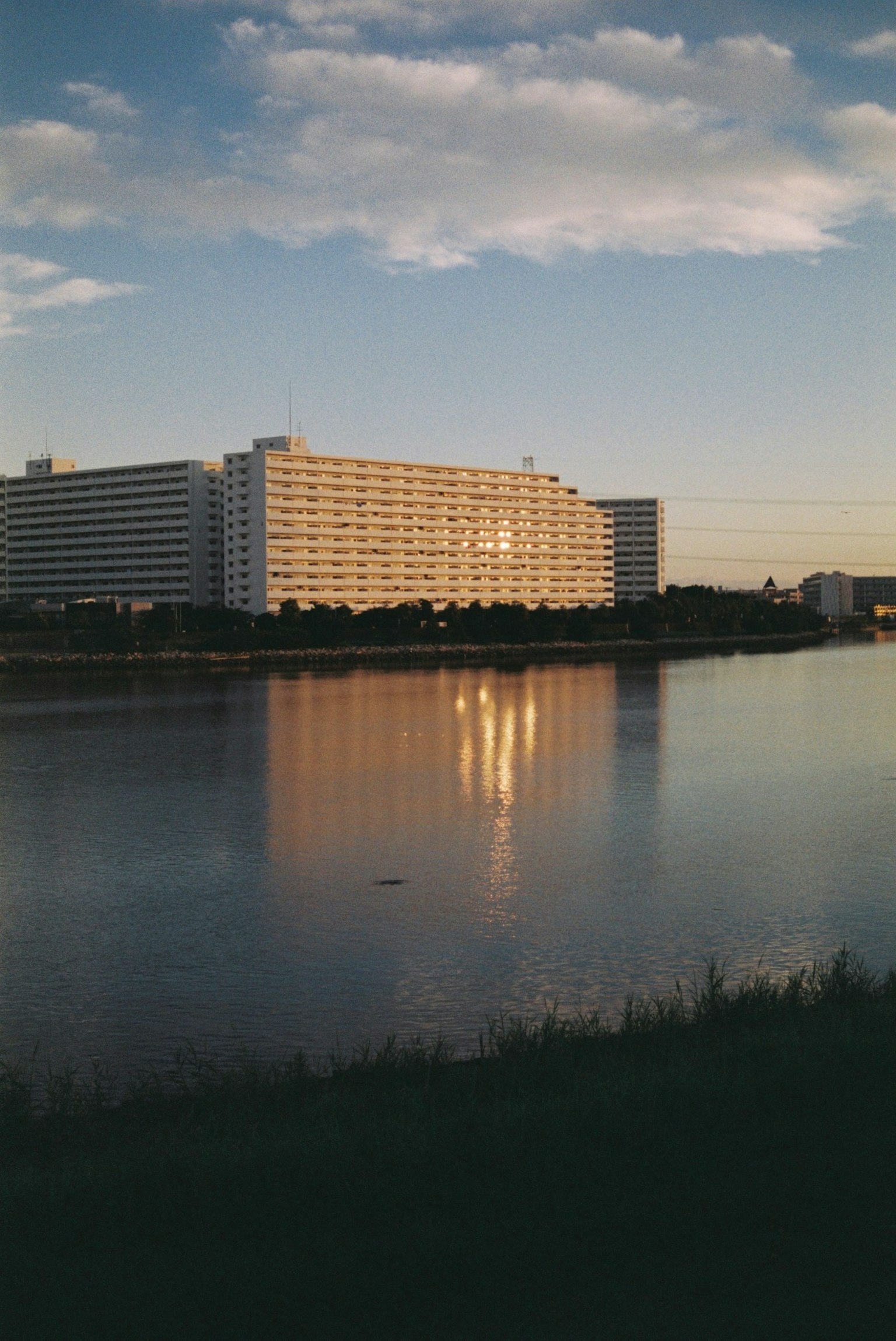 Edificio che si riflette nel fiume con un cielo colorato