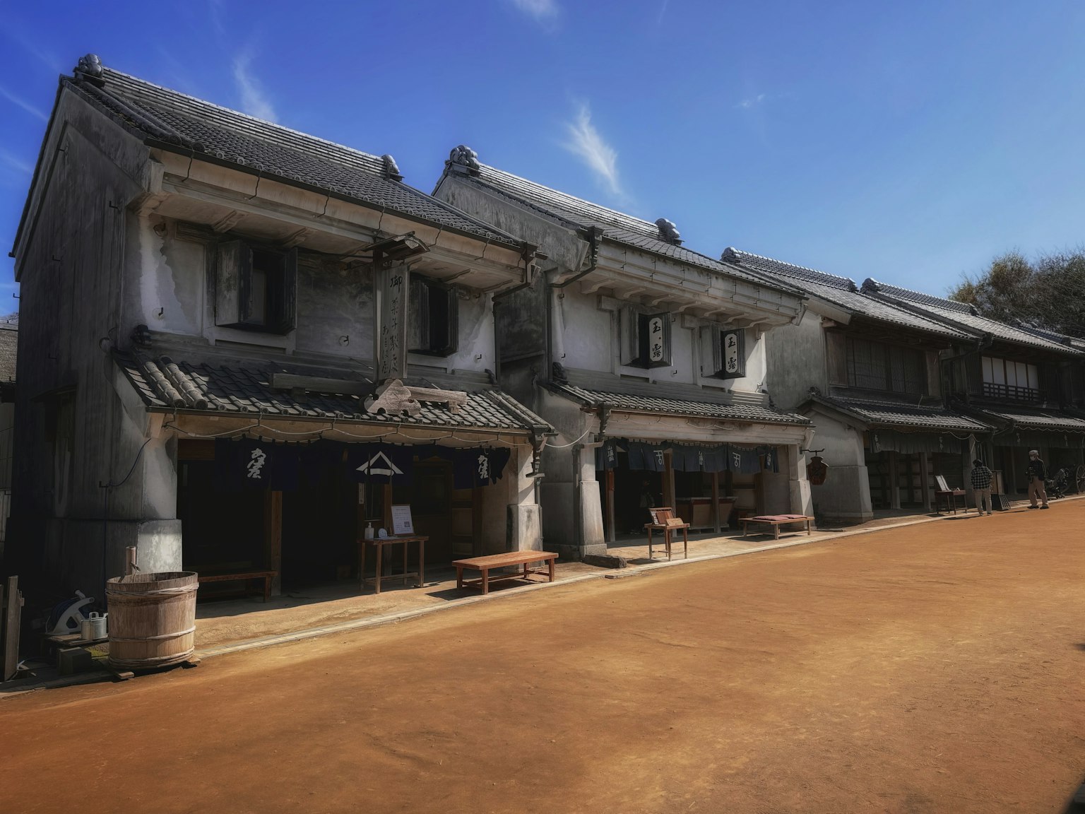 在晴朗的藍天下，沿著寬闊的土路排列的傳統日本建築
