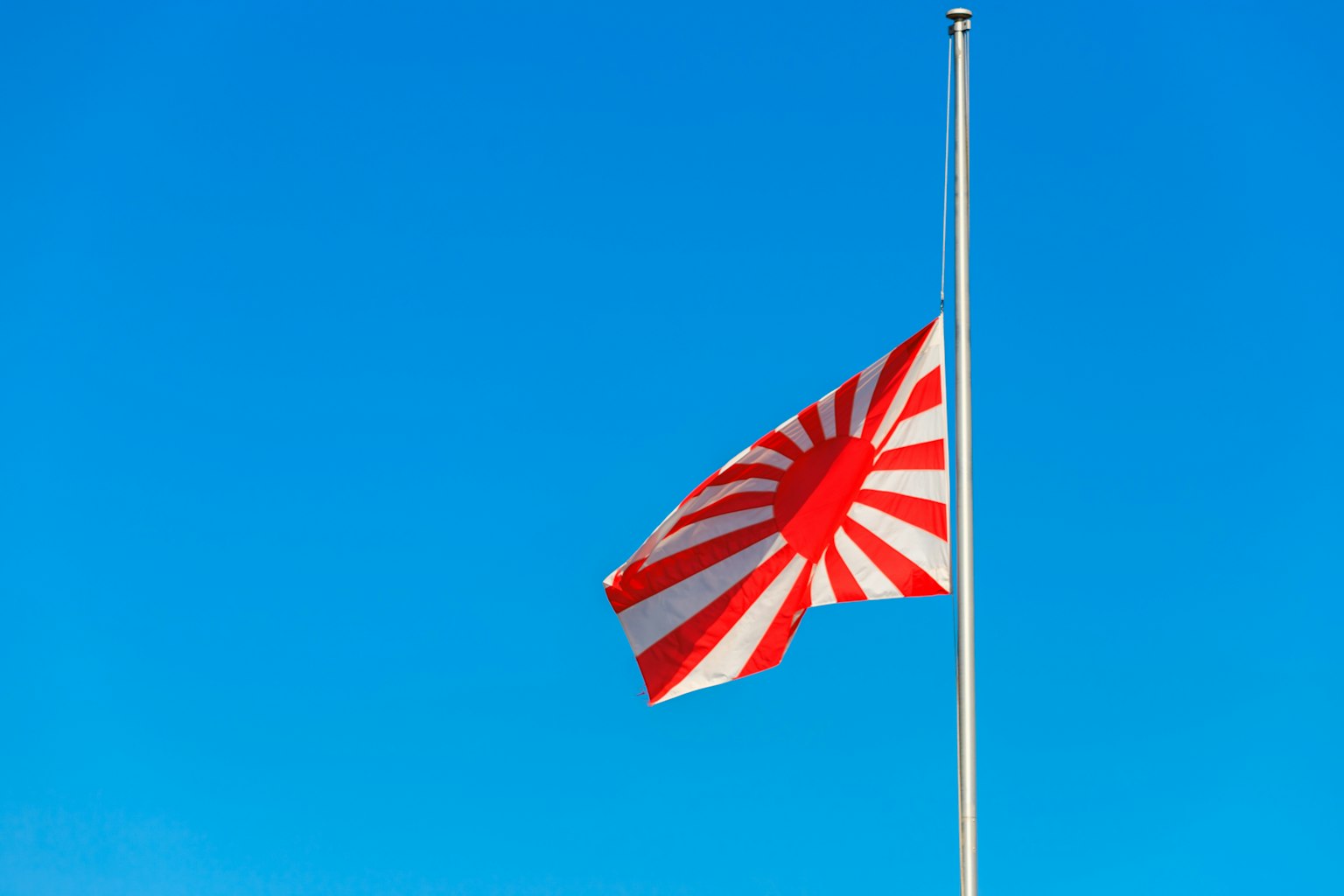 Rising sun flag waving under a blue sky