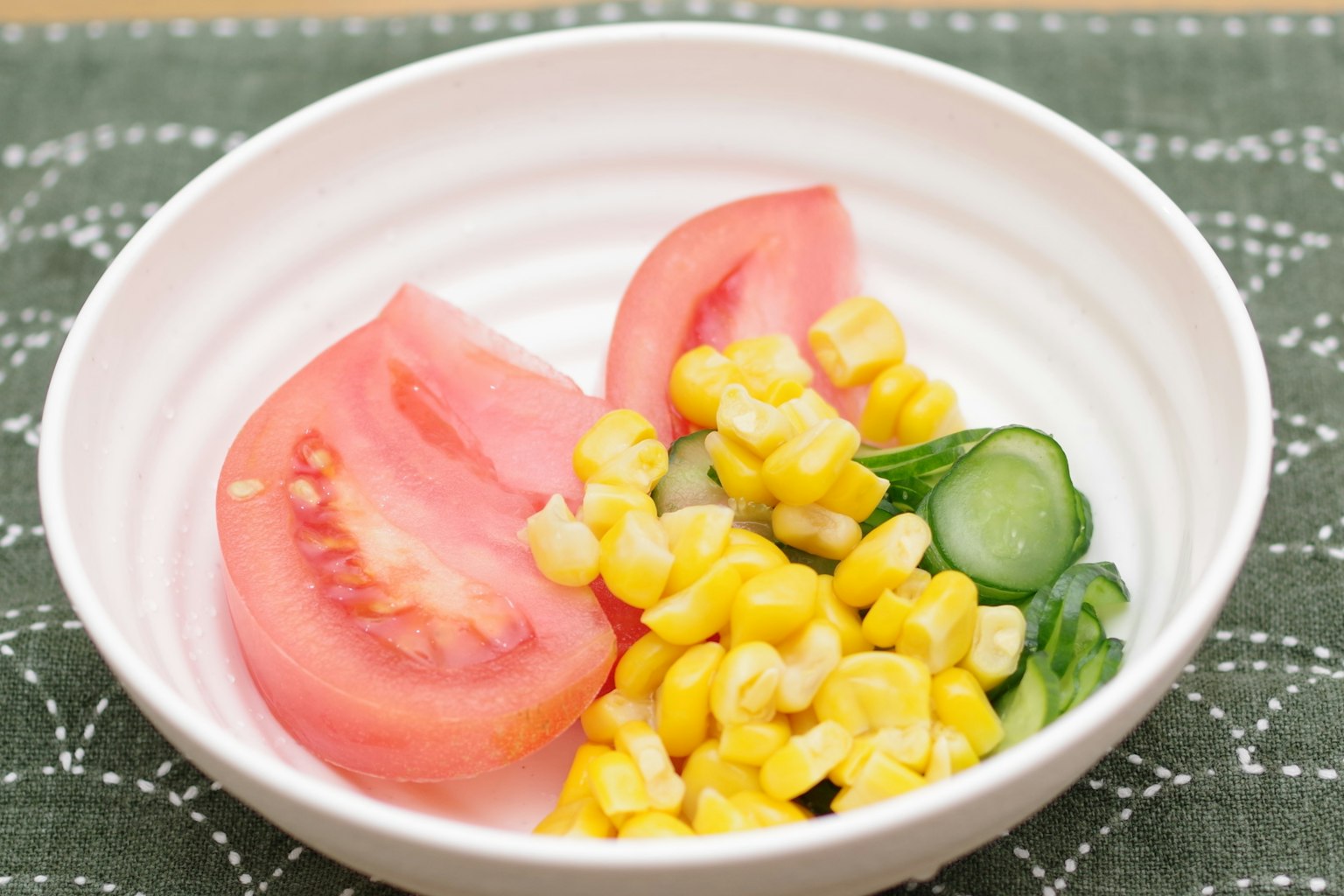 Salade de tomates en tranches maïs et concombres dans un bol blanc