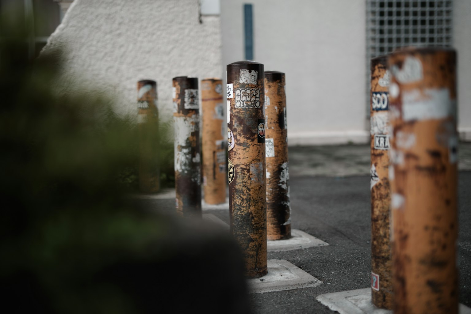 Row of weathered metal posts with rust and stickers