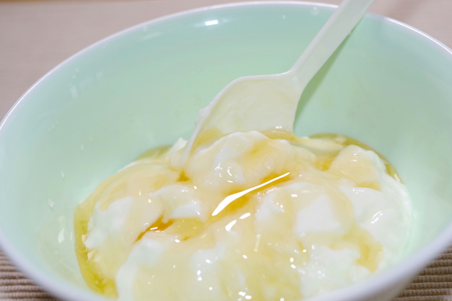 White yogurt drizzled with honey in a light green bowl
