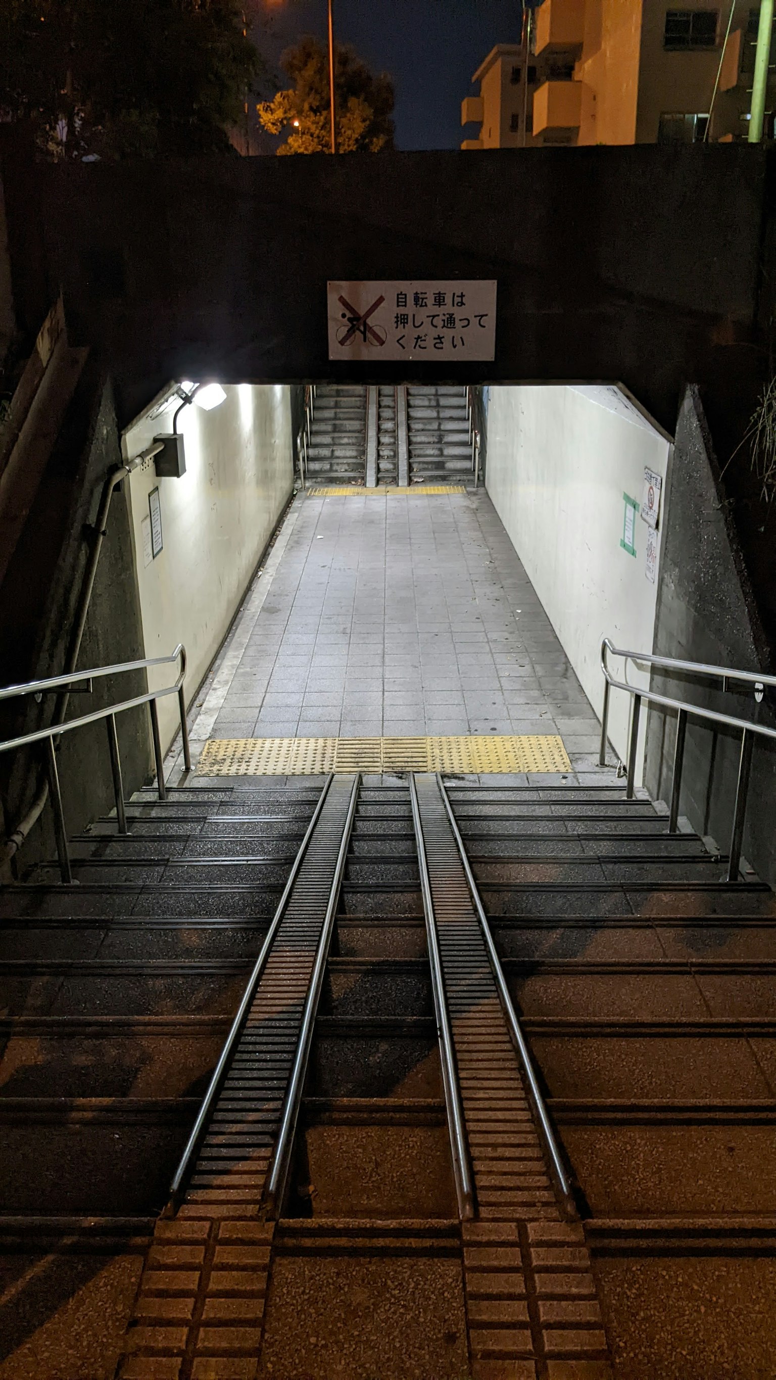 Escalera que conduce a un túnel con rieles y iluminación