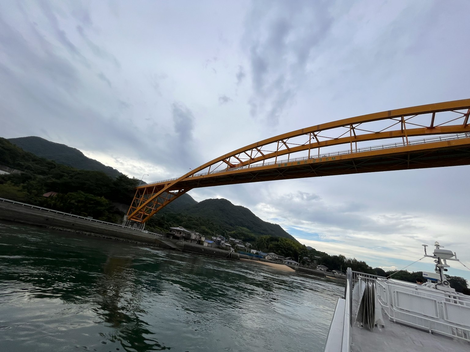 A beautiful yellow arch bridge spans across the mountains in the background