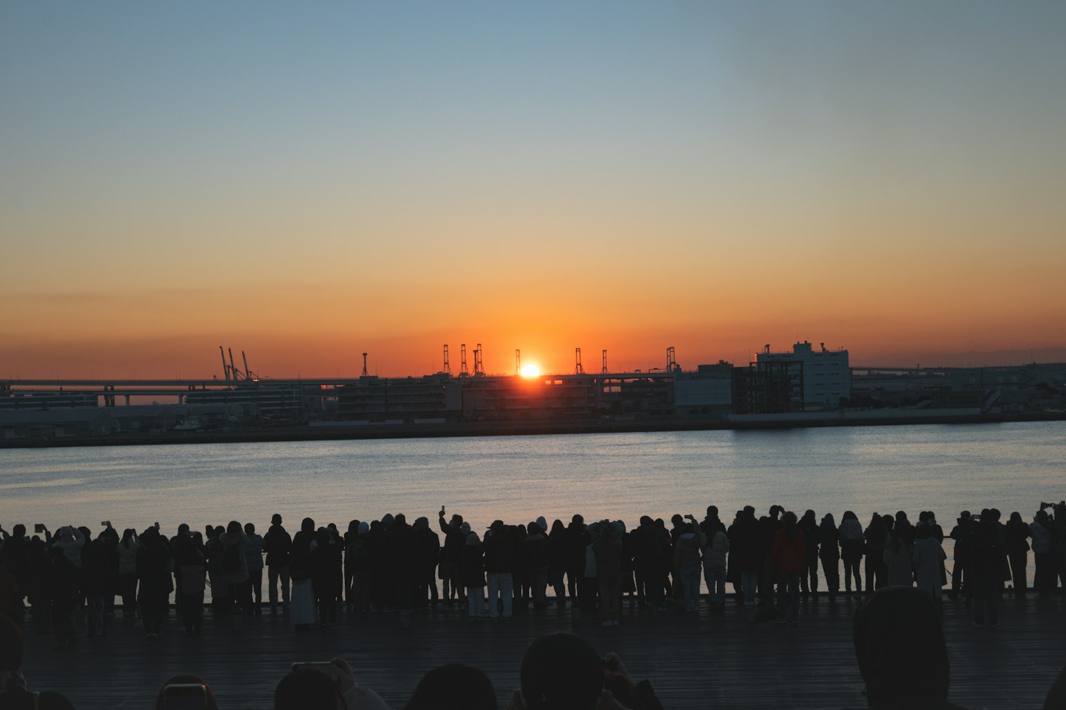 Silhouette von Menschen, die einen Sonnenuntergang am Wasser beobachten