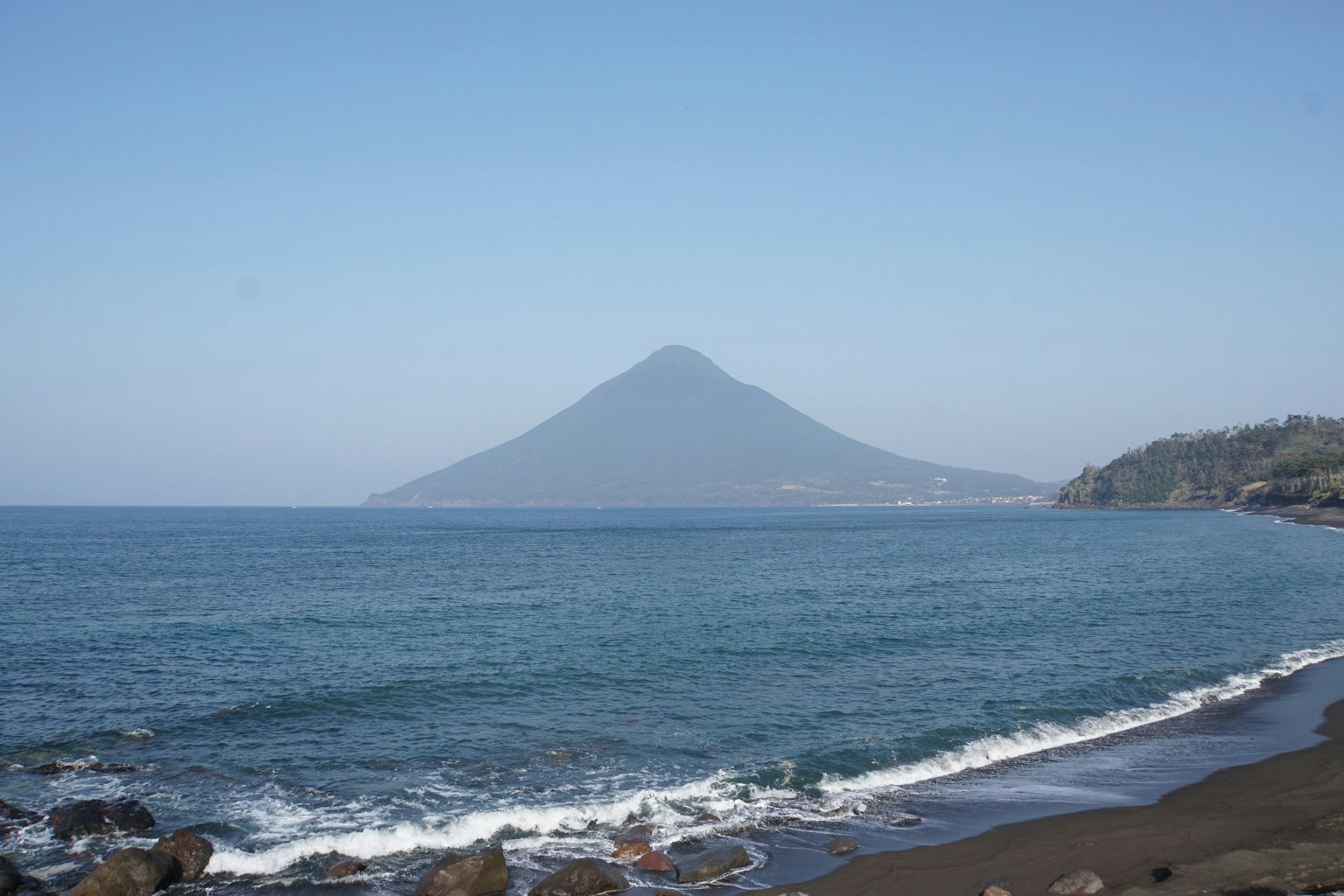 Paisaje montañoso con océano y playa de arena negra