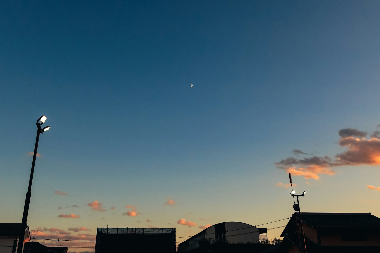 Cielo al crepuscolo con una luna crescente e strutture illuminate