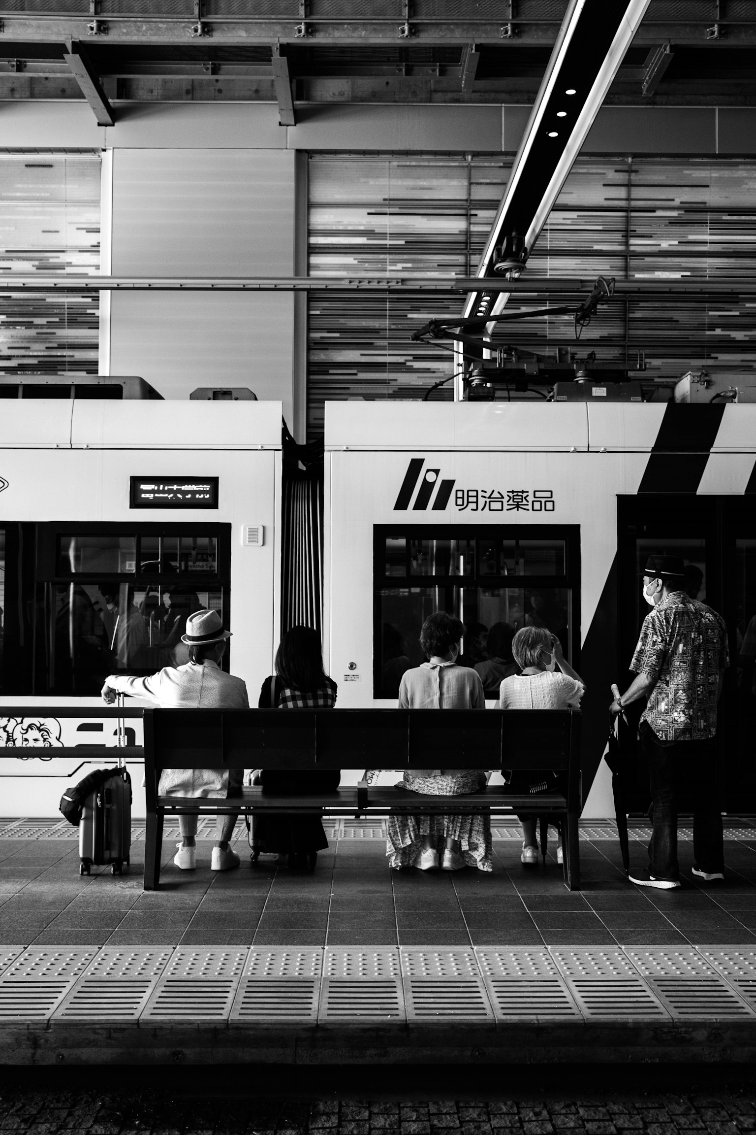 Foto in bianco e nero di persone in attesa su una banchina di treno