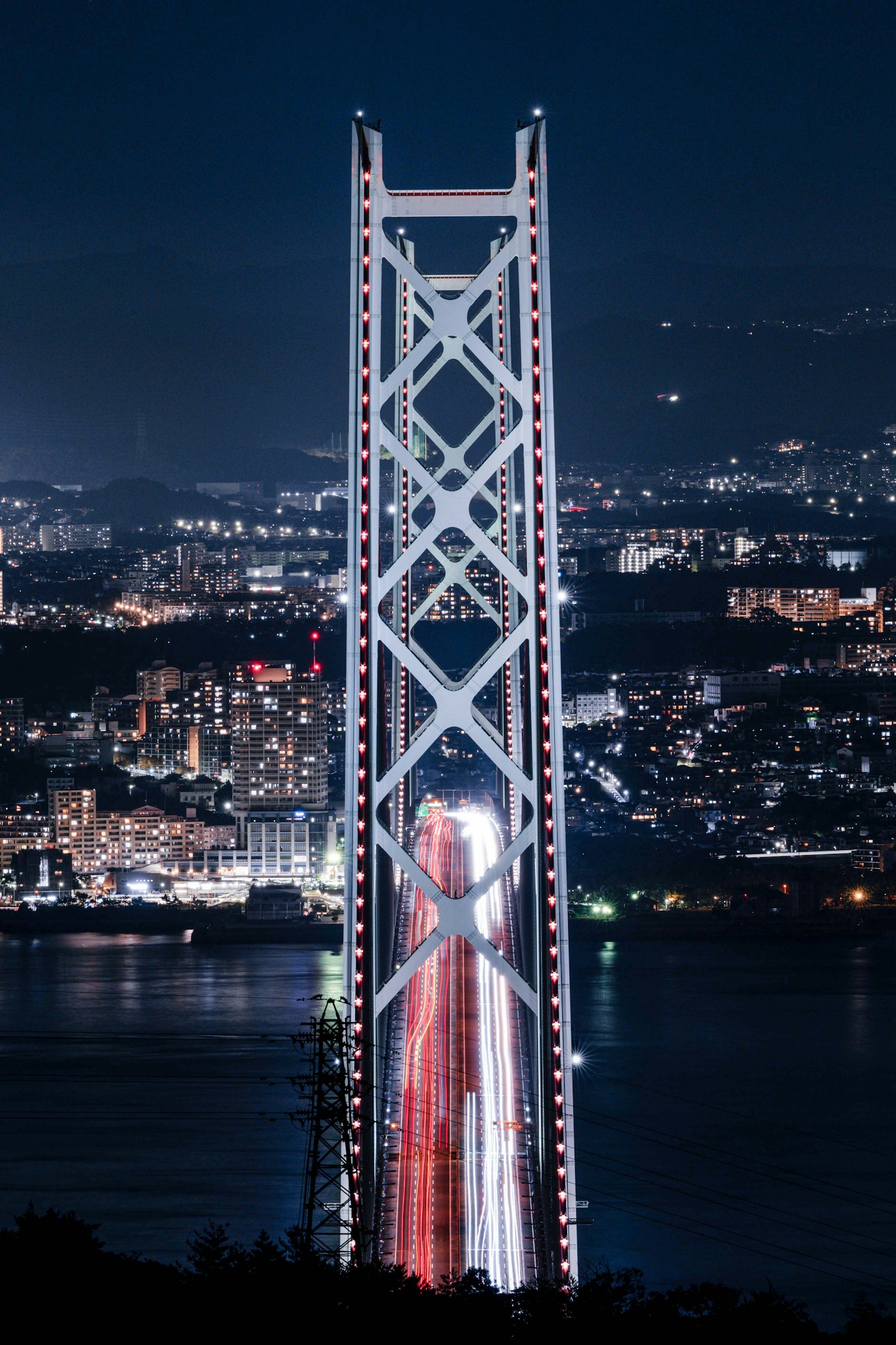 Structure de pont illuminée contre un horizon urbain nocturne
