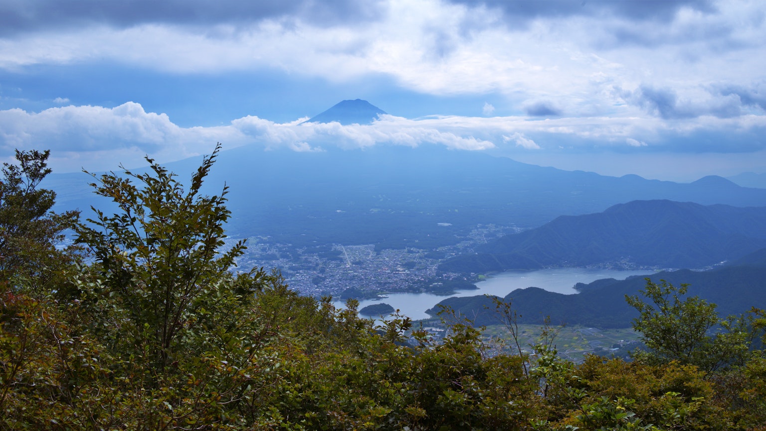 藍天和雲環繞的山景，背景中可見富士山