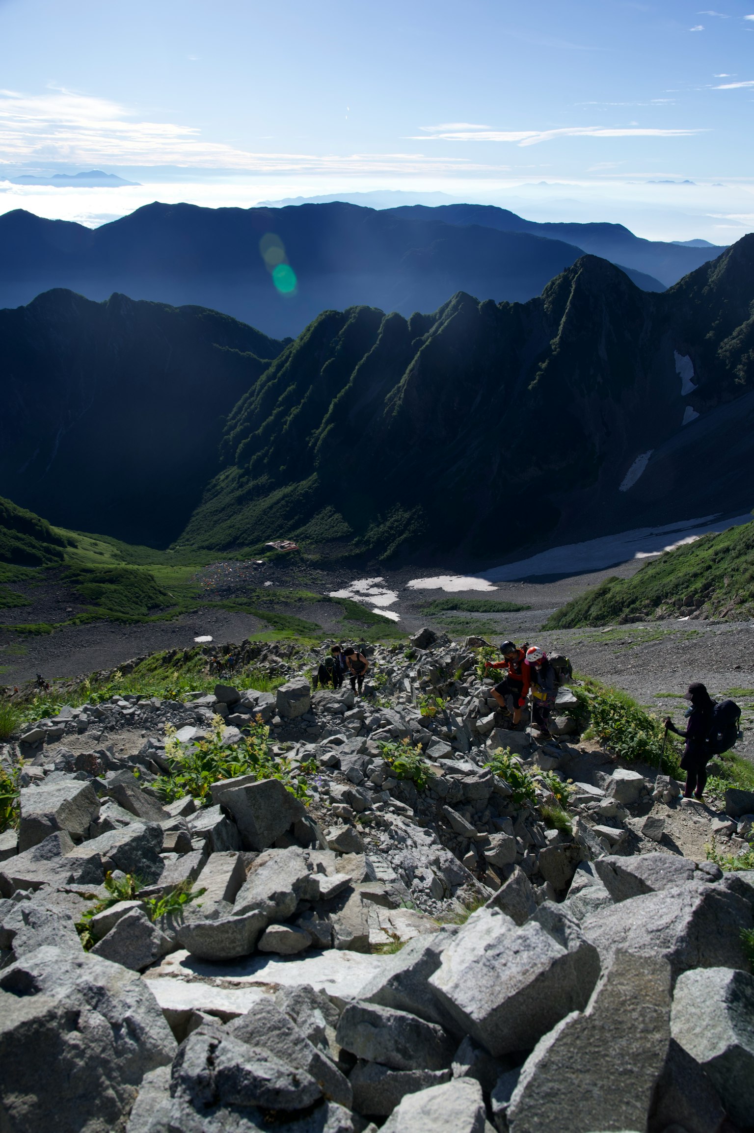 Wanderer steigen einen felsigen Bergpfad mit üppigem Grün hinauf