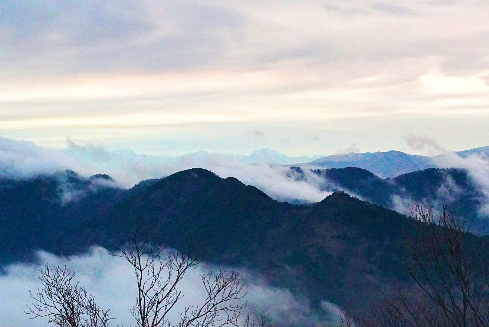 paysage de crêtes montagneuses enveloppées de brume et mer de nuages
