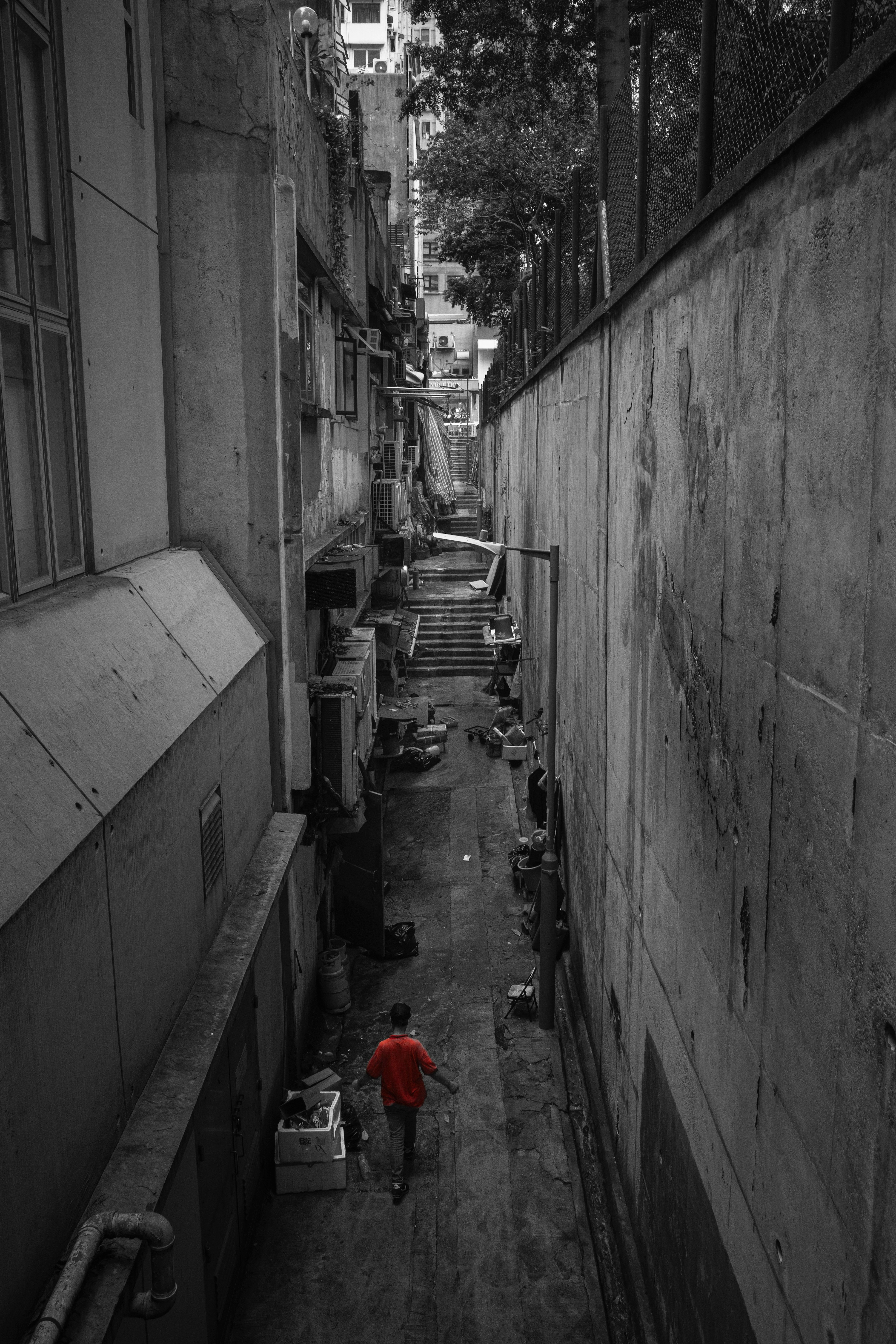 狭い路地を歩く赤い服の人物と周囲のモノクロの背景