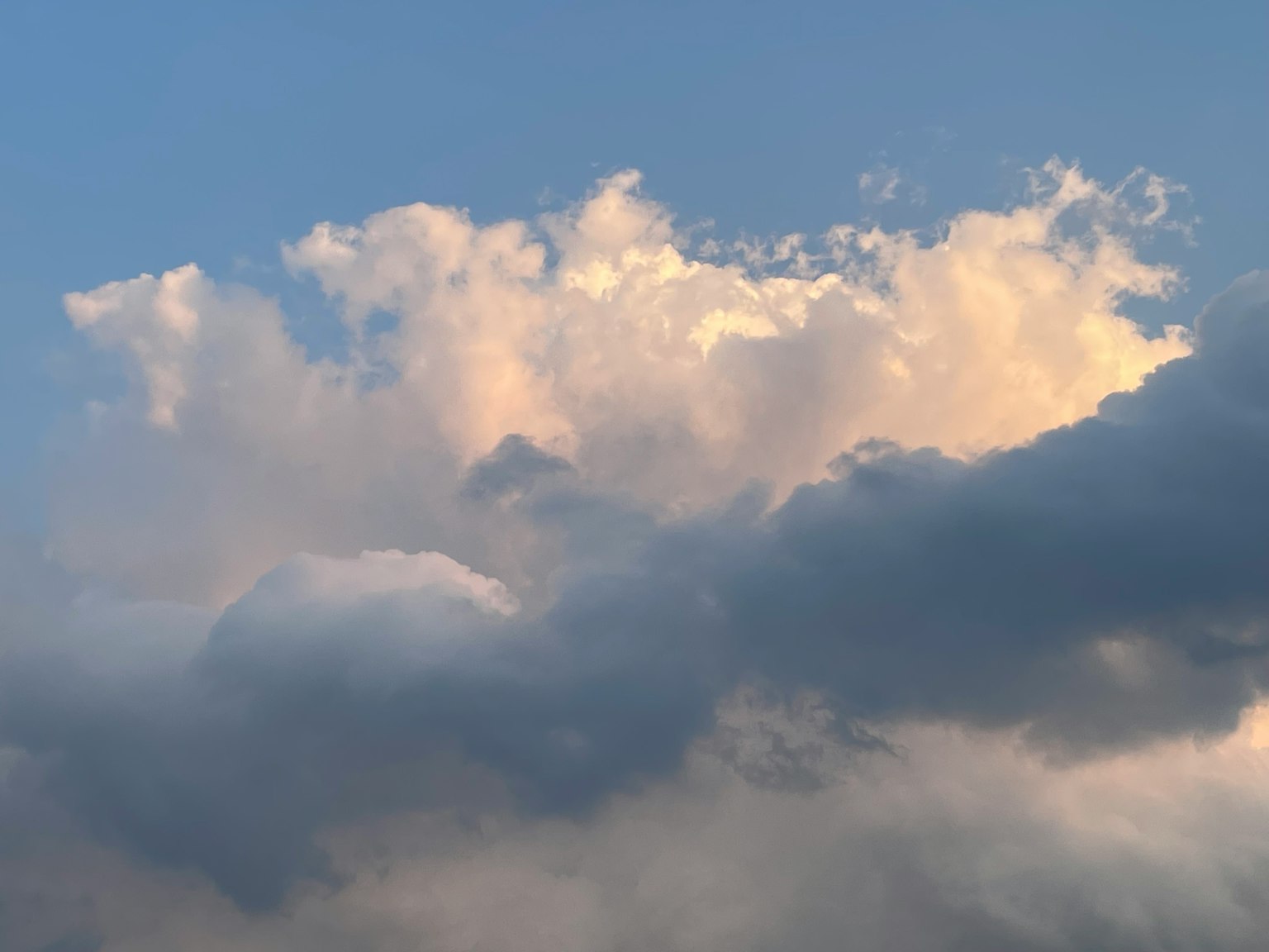 Nubes blancas esponjosas iluminadas por una luz suave contra un cielo azul