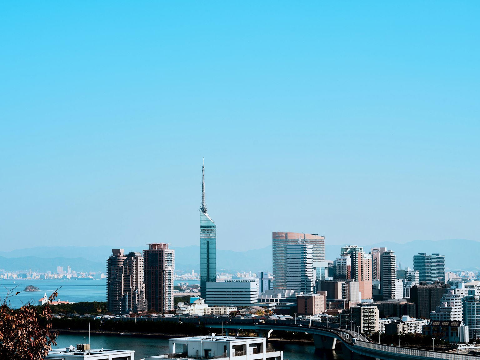 福冈市的城市景观，背景为福冈塔和晴朗的蓝天
