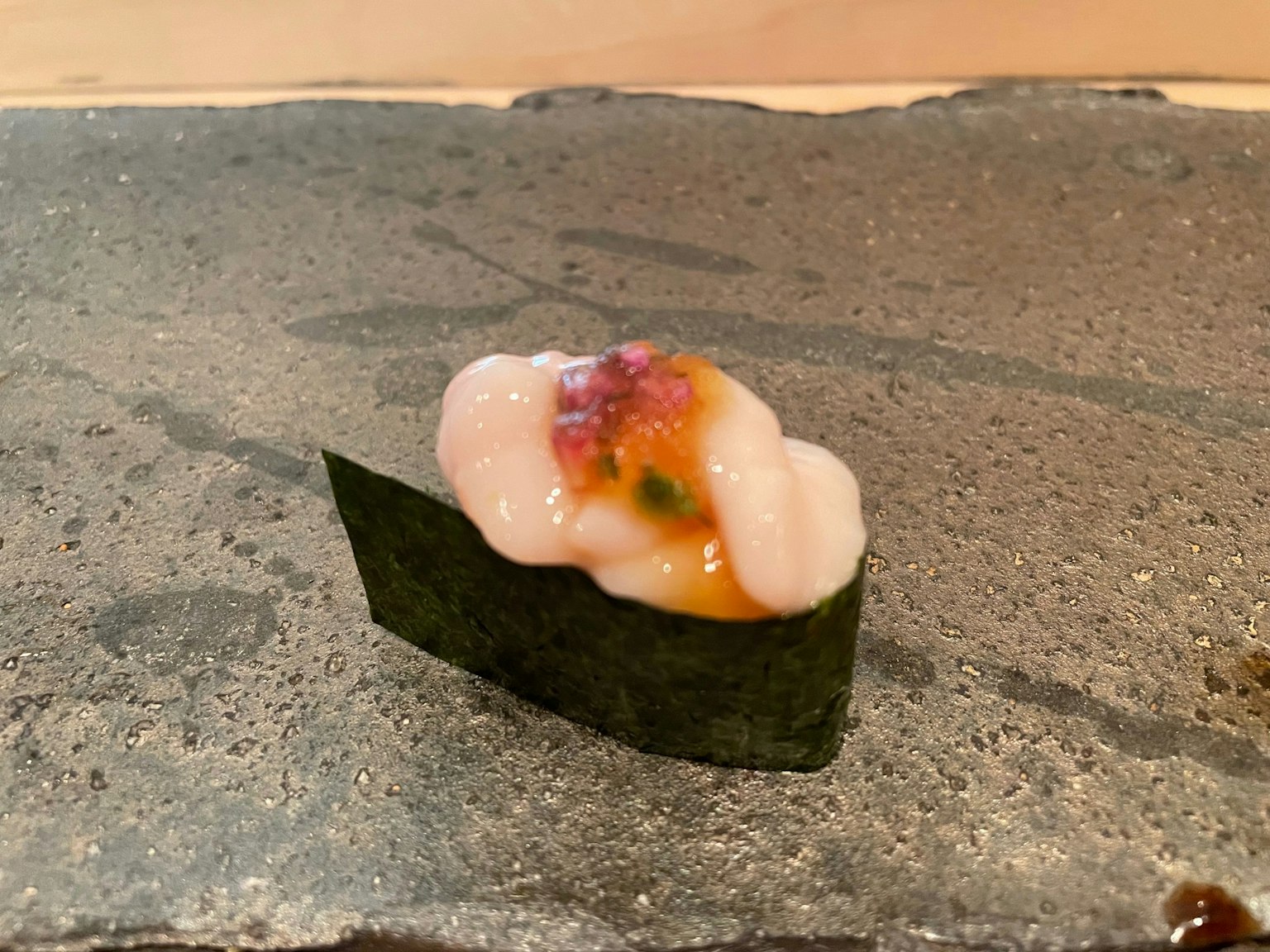 Pièce de sushi sur une surface en pierre noire avec un garniture unique enveloppée d'algue