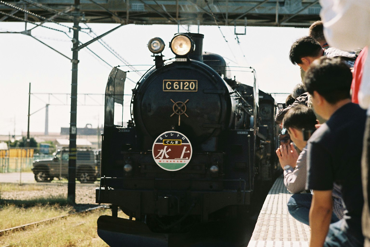 Una locomotora de vapor negra en una estación con pasajeros observando