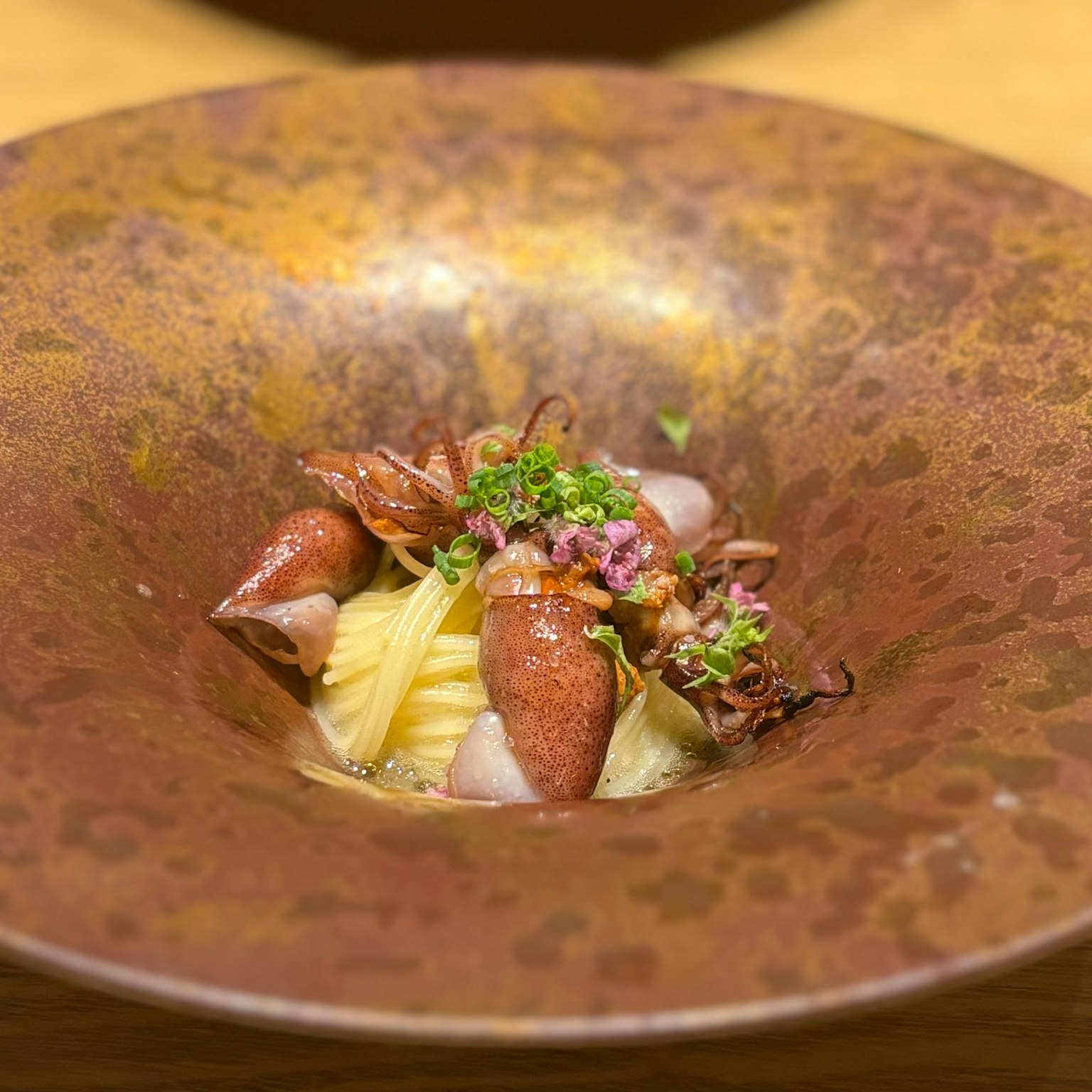 A beautifully plated pasta dish with shrimp in a rustic brown bowl
