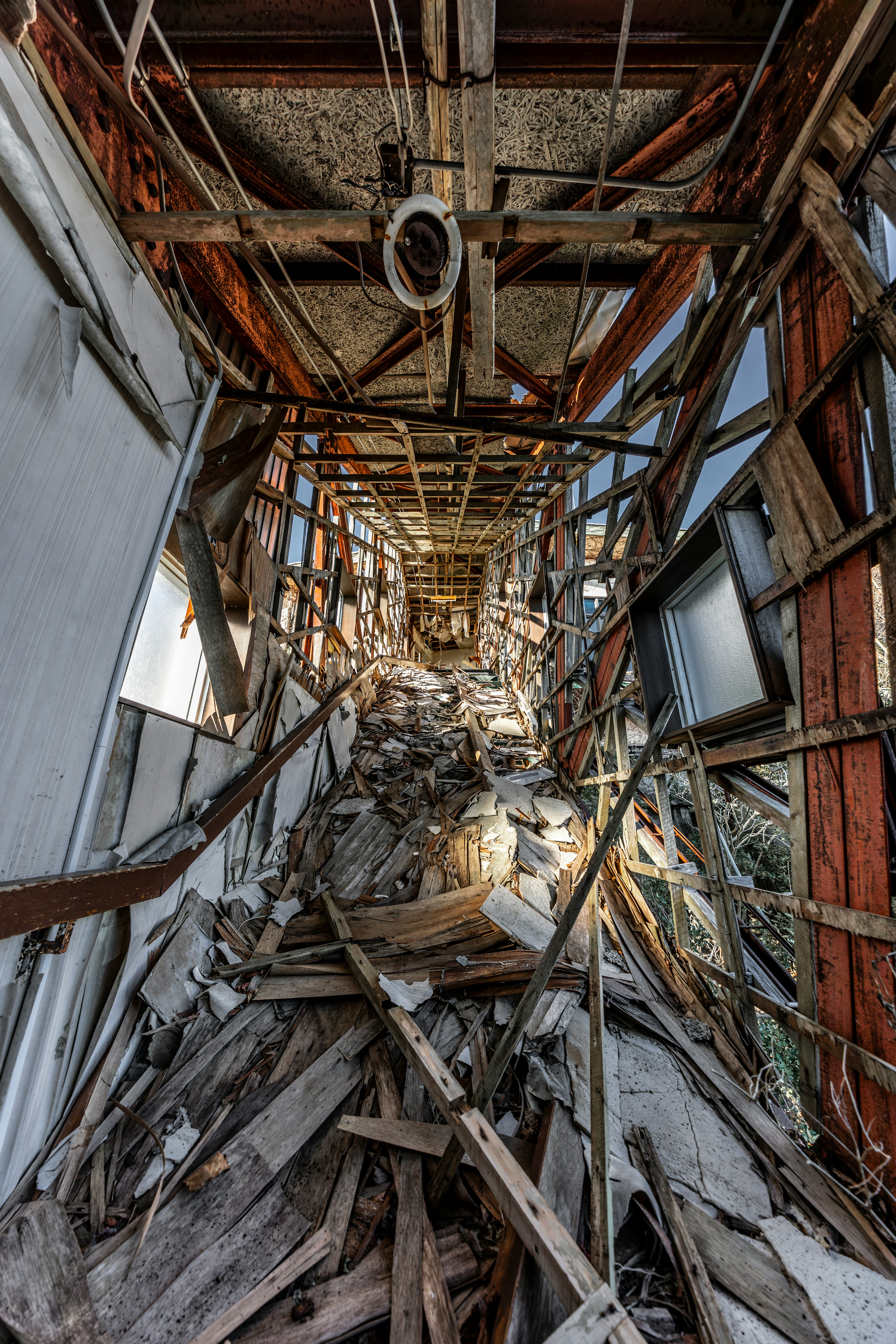 A ruined corridor in an abandoned building with exposed steel beams and debris