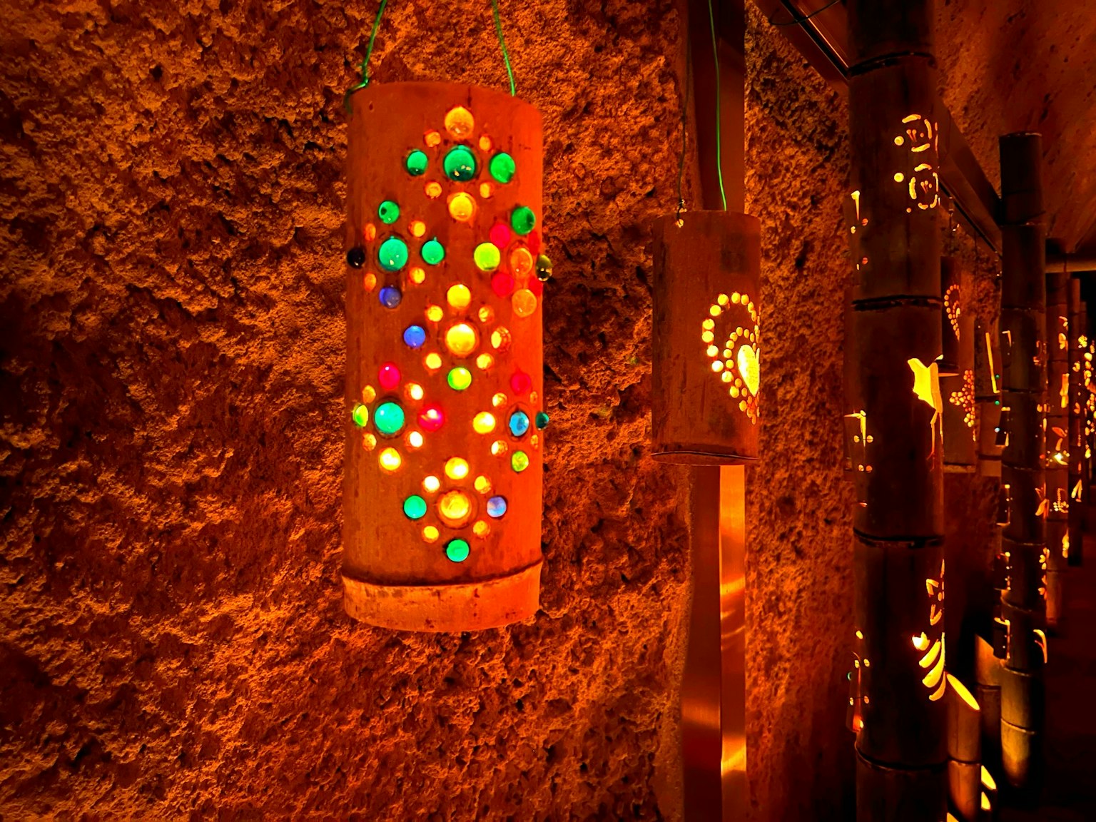 Lanterna colorata con luci decorative appesa a un muro testurizzato in un ambiente caldo