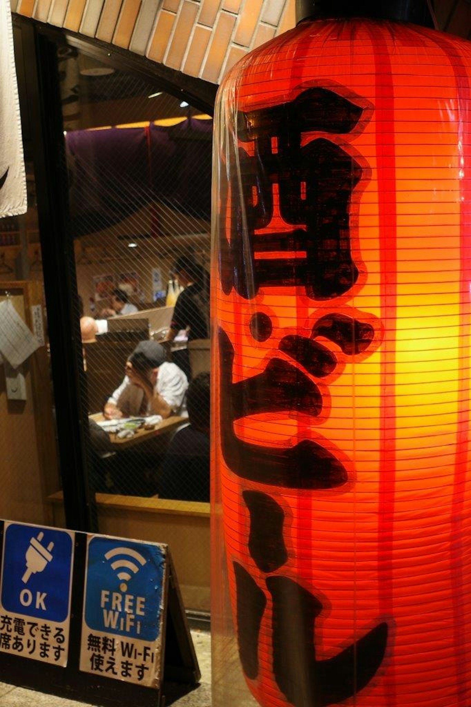 Linterna roja con caracteres japoneses y cartel de Wi-Fi gratuito afuera de un restaurante