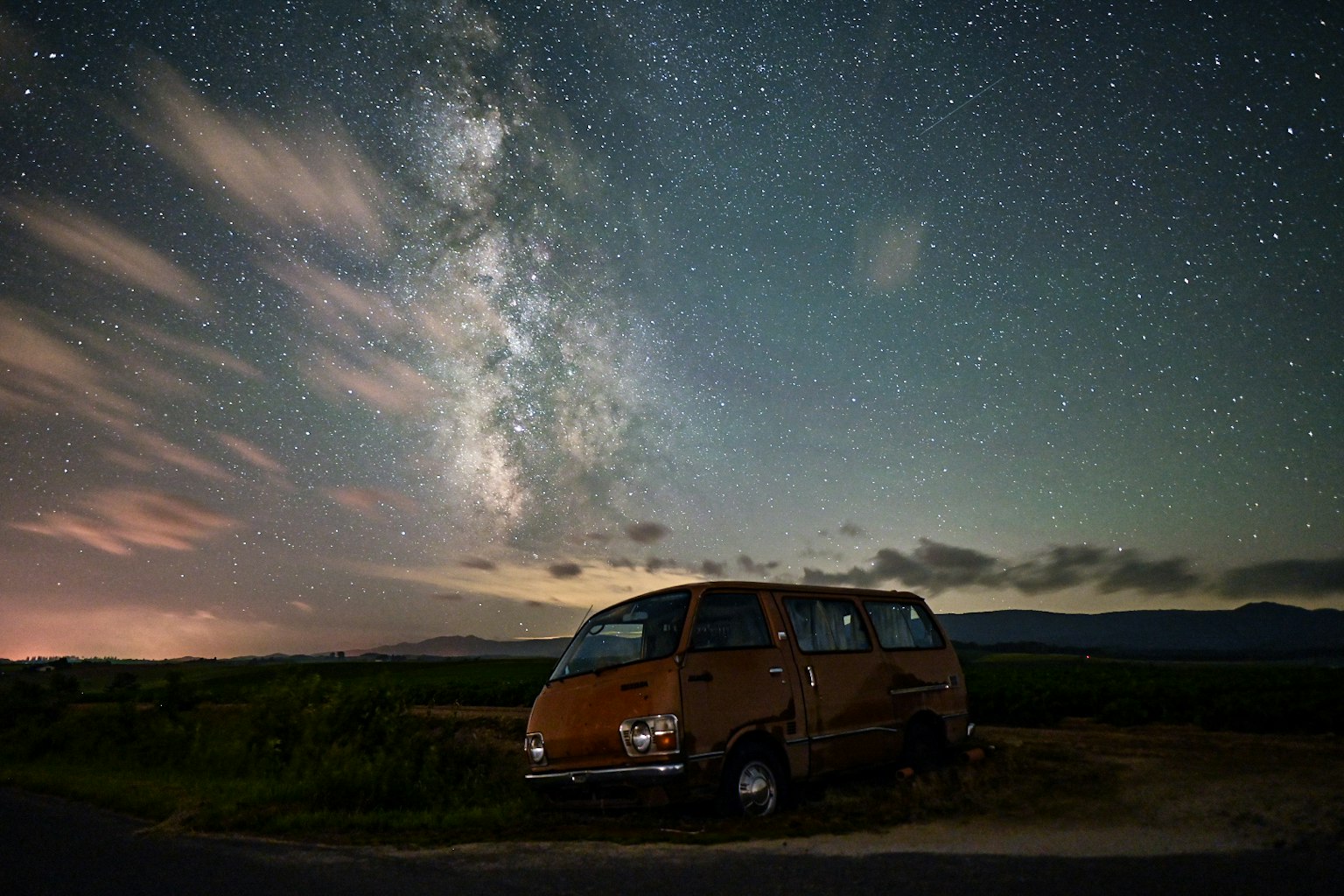 Orange van parked under a starry sky with the Milky Way