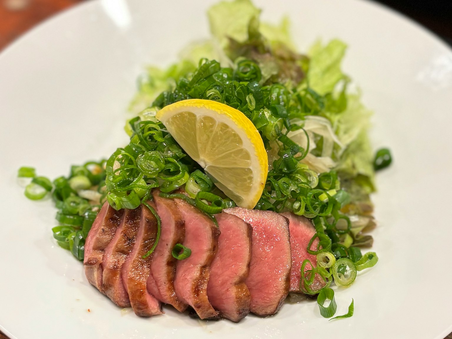 Carne affettata con cipollotti e insalata guarnita con limone