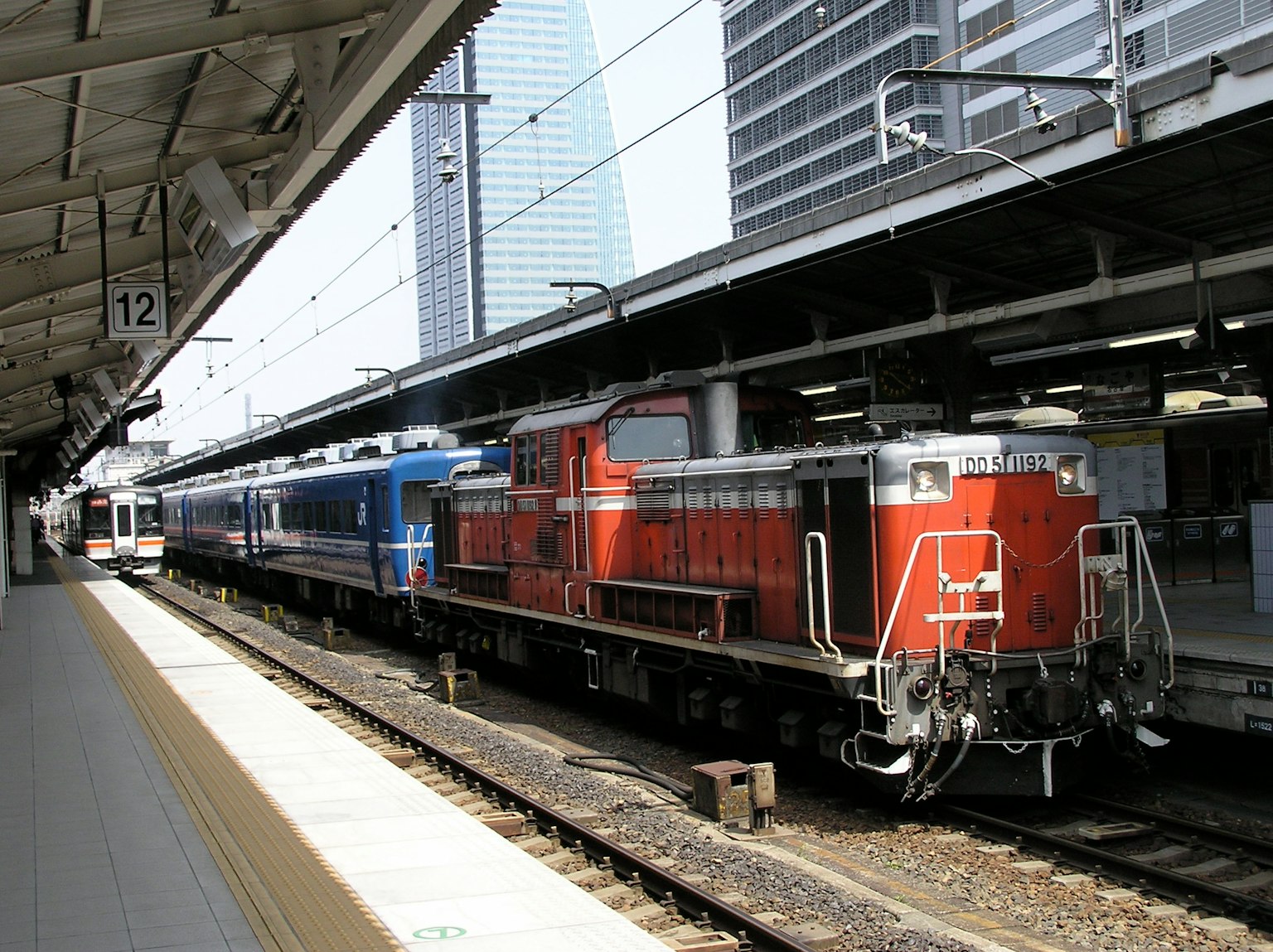 Lokomotif merah dan kereta penumpang biru di stasiun
