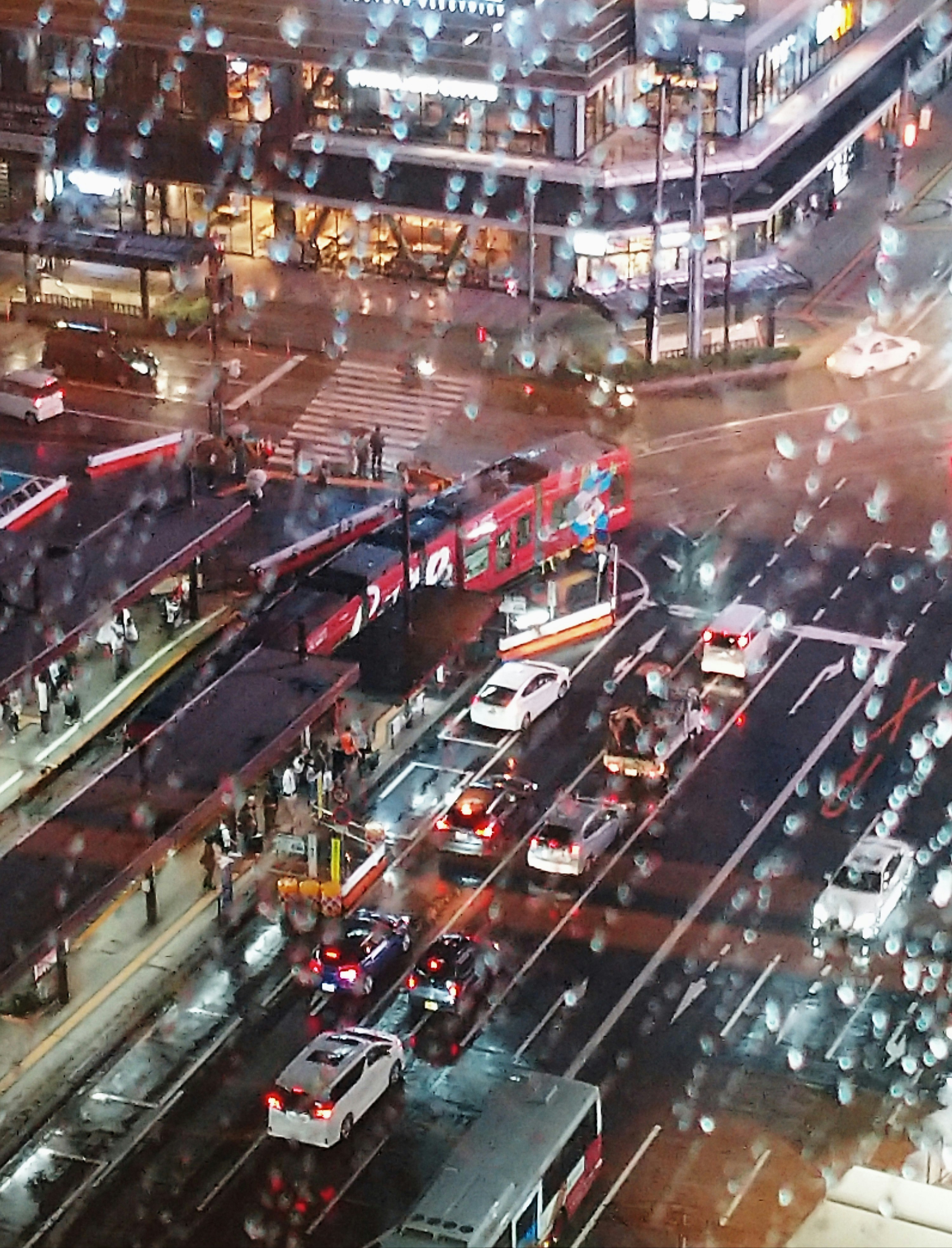 雨の中の広島の電車が走る駅前の交差点