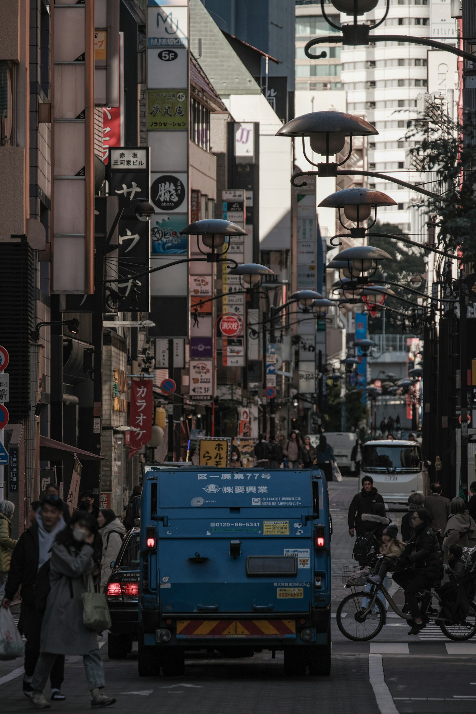 繁華街道場景，藍色車輛和行人