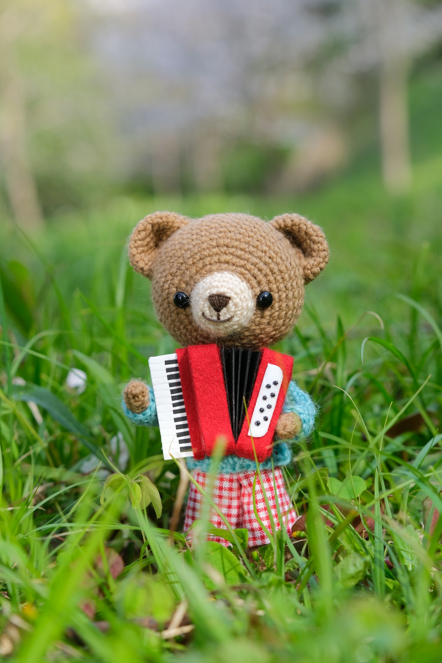 Ours en crochet tenant un accordéon debout dans l'herbe verte