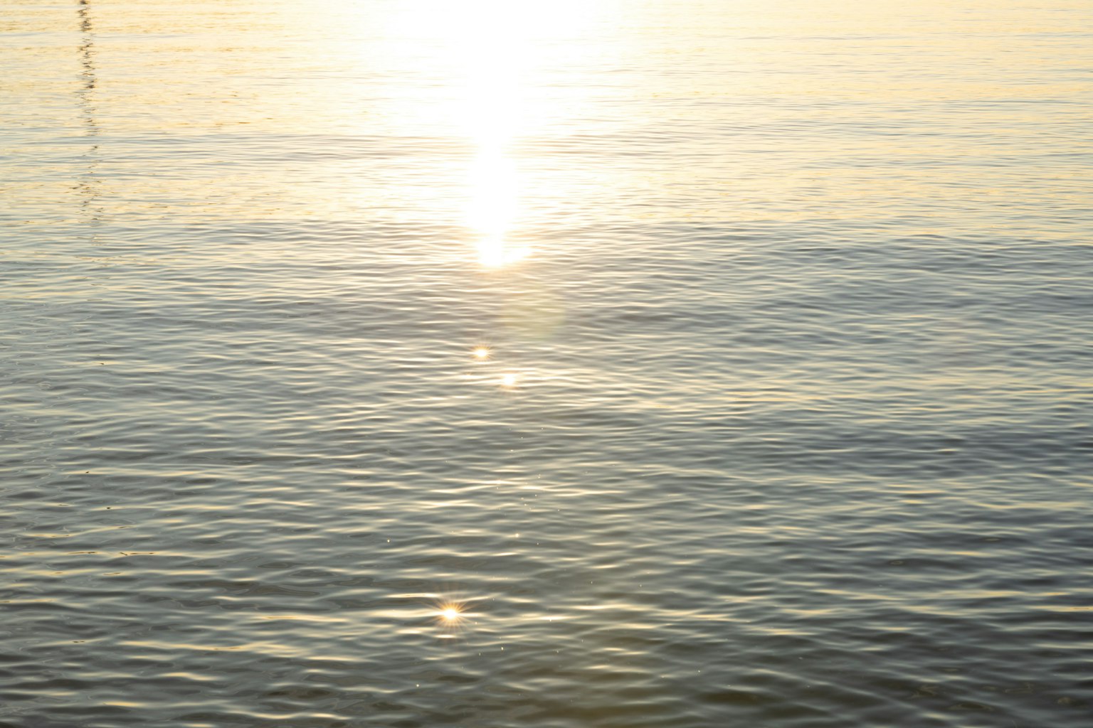 Superficie de agua tranquila reflejando la luz del sol