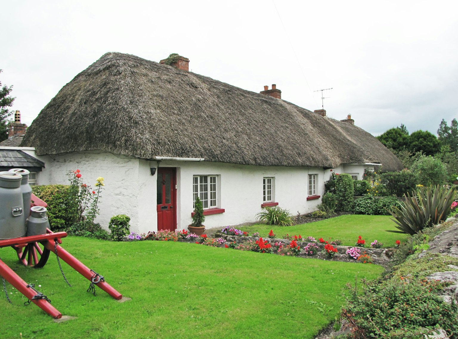 Charming thatched-roof cottage with white walls and a colorful garden