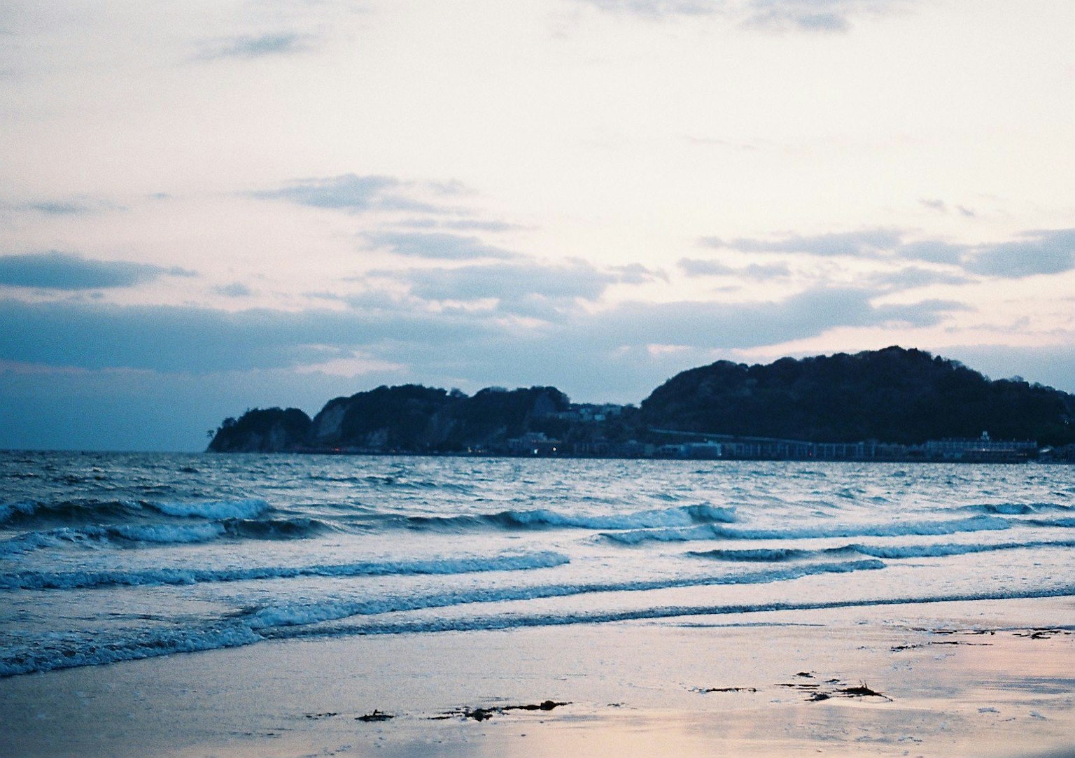 宁静的海滩黄昏景色，海浪和远处的山丘
