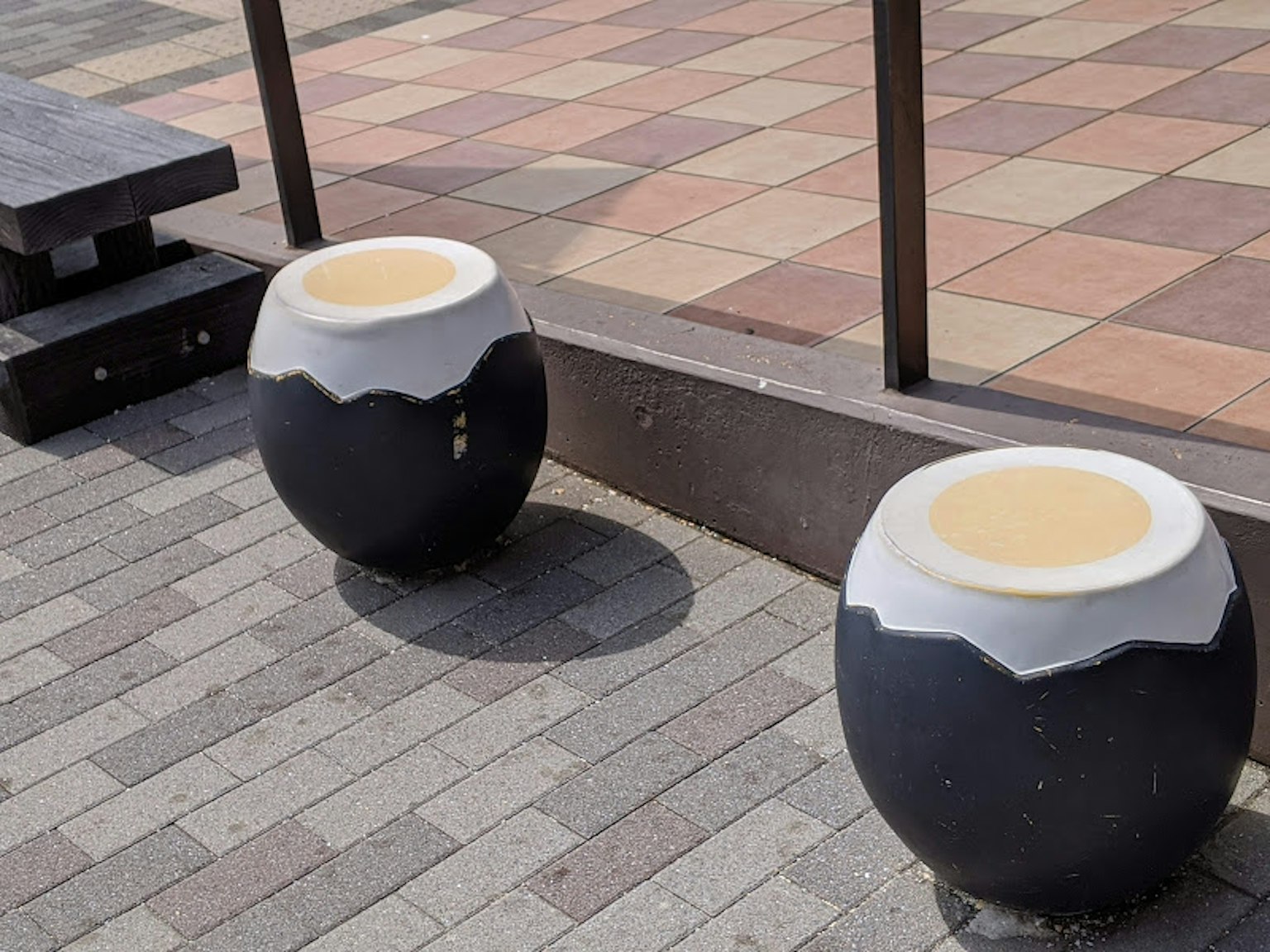 Two black and white egg-shaped objects in an outdoor seating area