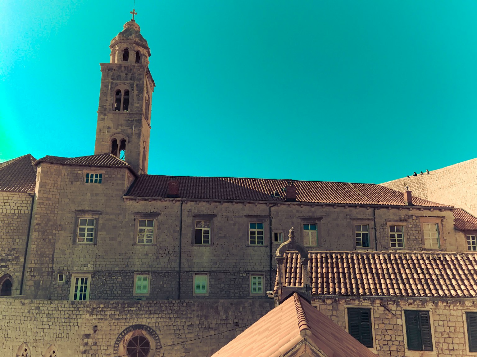 Edificio histórico de piedra con una torre bajo un cielo azul