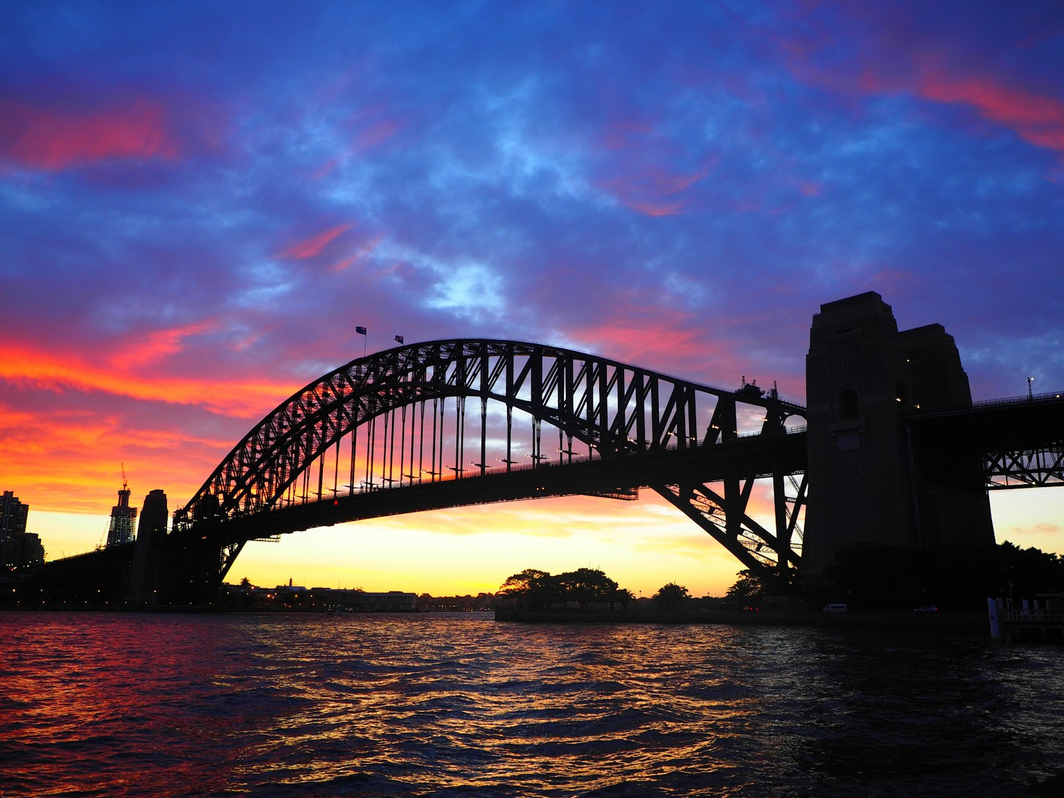 Jembatan Pelabuhan Sydney bersiluet melawan langit senja yang cerah