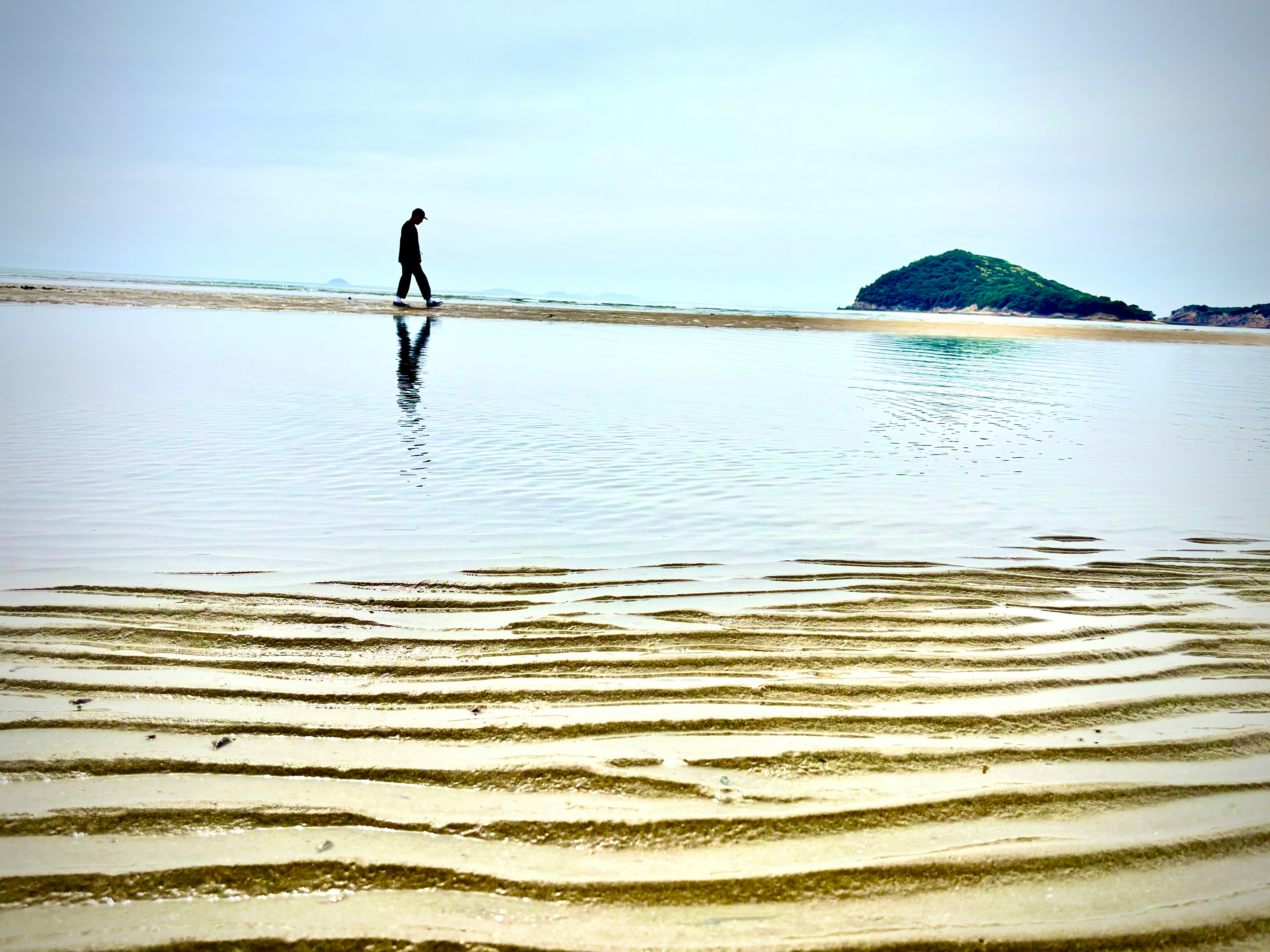 秩父が浜の広い砂浜と海辺を歩く人のいる風景