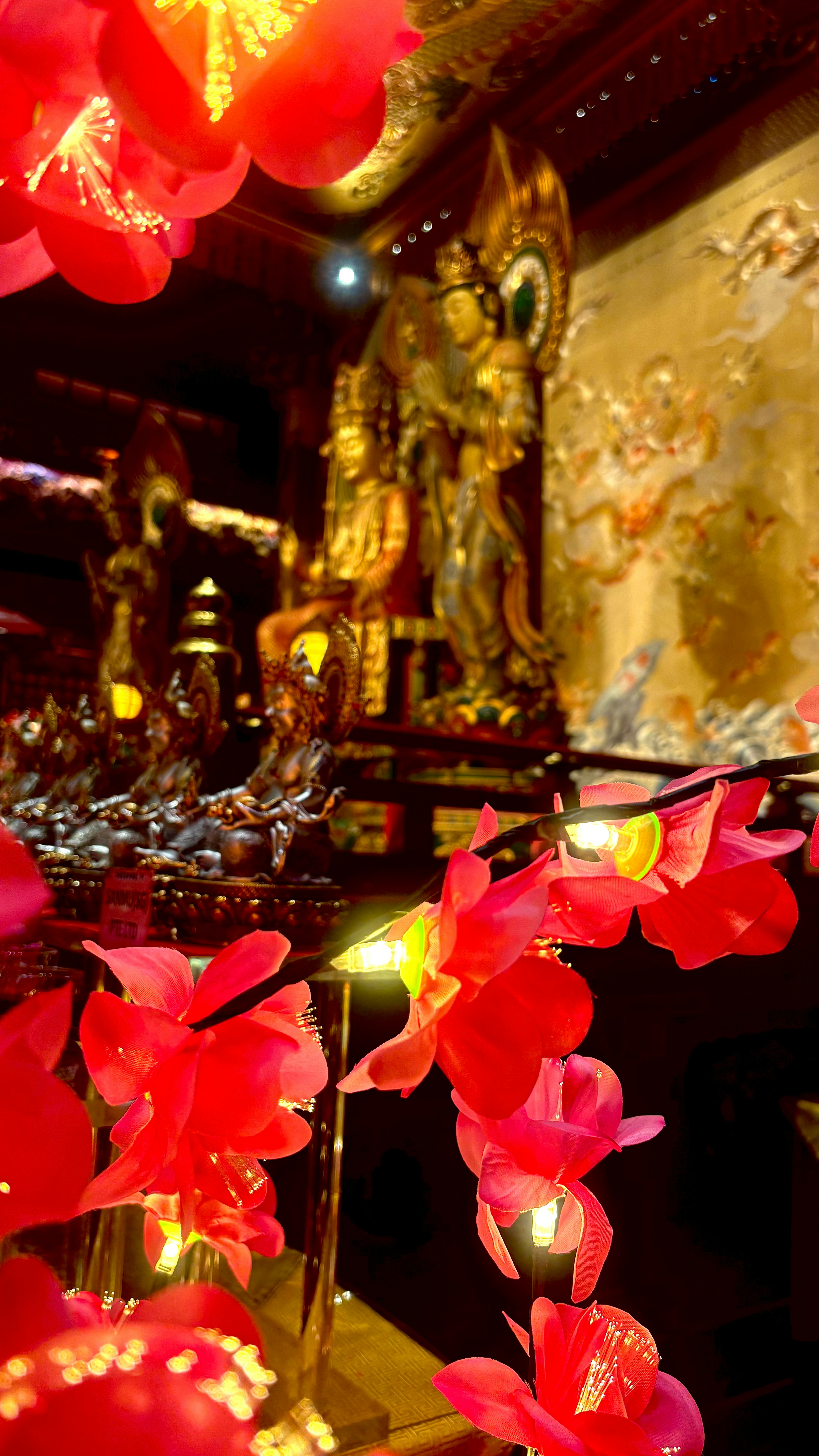 鲜艳的红花和寺庙内的金色雕塑